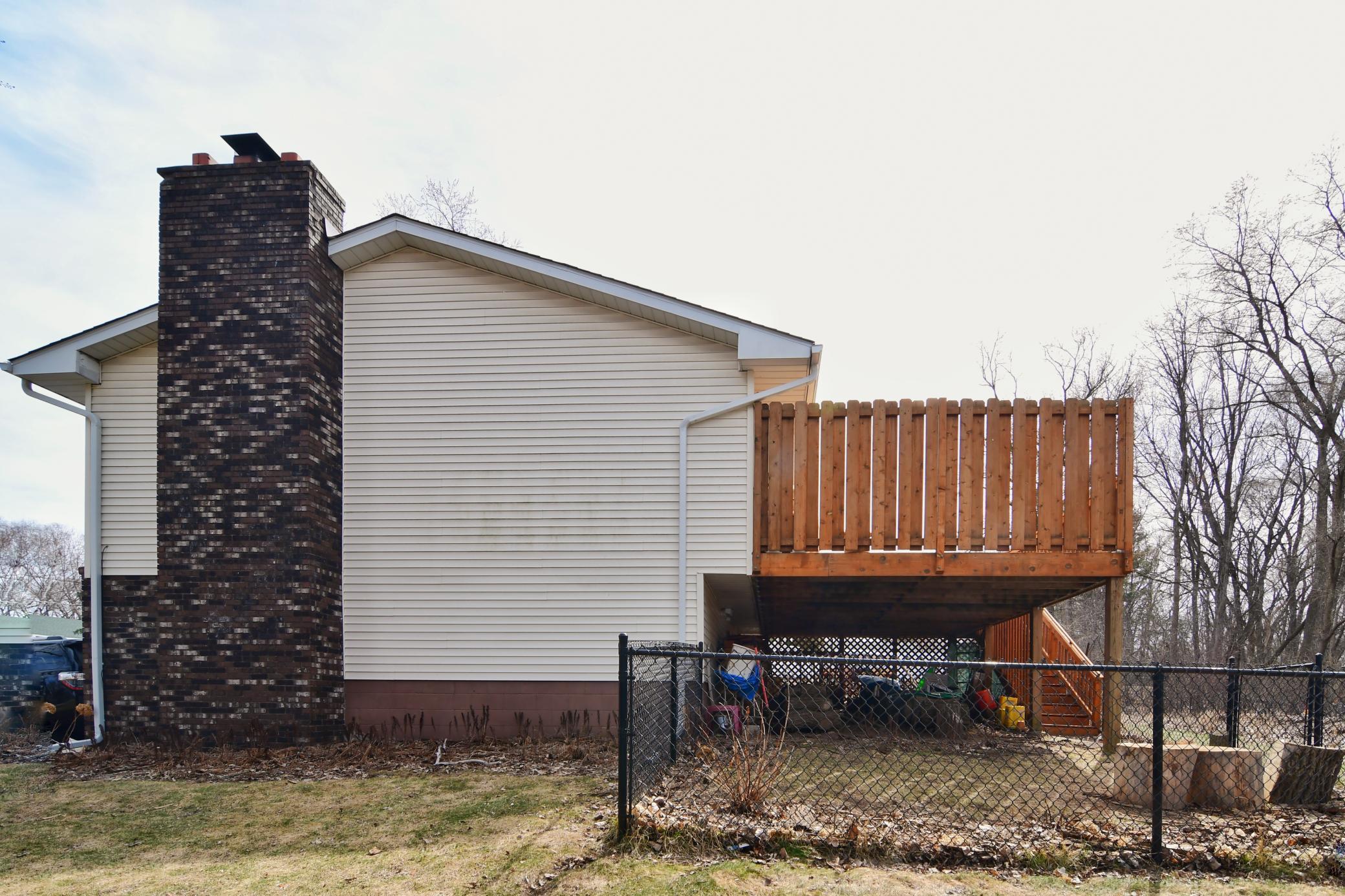 The brick chimney adds architectural interest to the exterior and coordinates with the black fence and light hue siding.