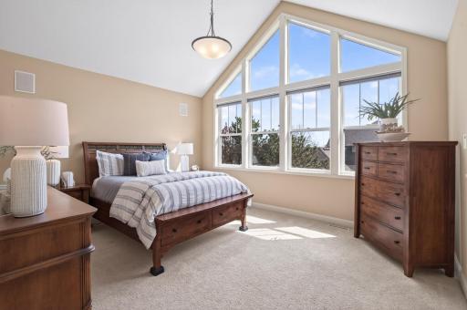 Escape to this elegant primary bedroom where dramatic architectural lines meet cozy comfort; Featuring soaring vaulted ceilings and ample room for king-sized furnishings, it serves as a spacious sanctuary for rest and relaxation