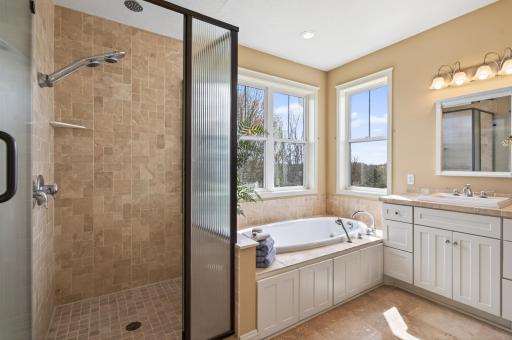 A true spa-at-home experience. This tranquil primary ensuite is anchored by a deep jetted soaking tub and a separate, modern glass-enclosed shower with custom tile work