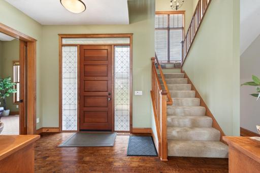 Wide staircase, multi-paned window and an ornamental iron chandelier, creating a stunning, warm transition between floors