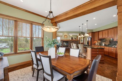 This dining room strikes a warm, inviting balance between elegance and comfort. Framed by rich wood trim and architectural columns, the space feels both defined and open, seamlessly connecting to the kitchen beyond