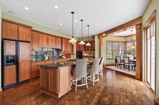 Beautifully designed open-concept kitchen and dining space showcasing rich warm wood cabinetry, granite countertops, and a spacious center island