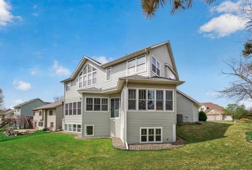 Stunning rear view highlighting the home's grand scale and architectural detail. Featuring expansive windows, and a meticulously manicured lawn, this property shines from every angle