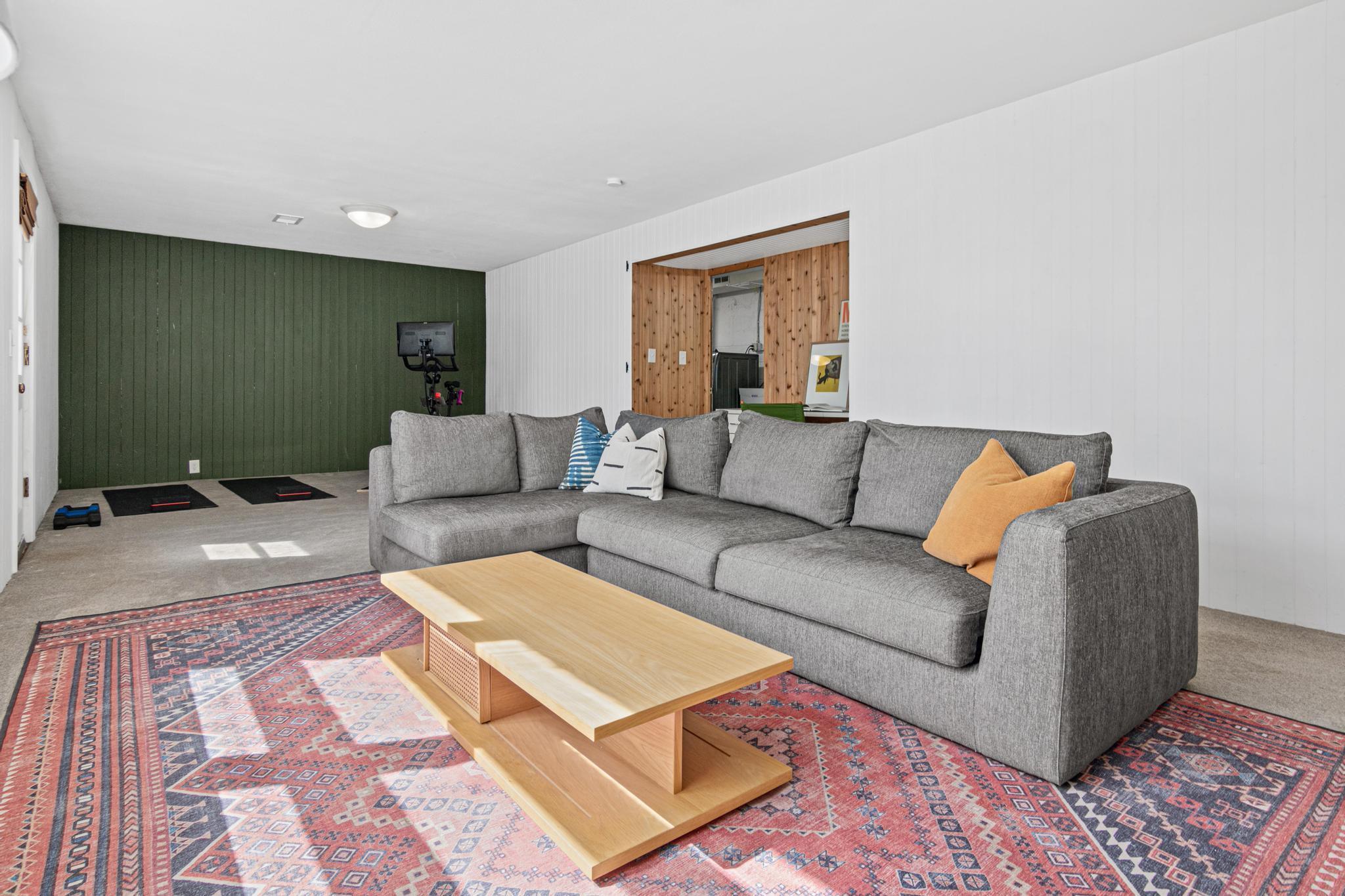 The lower level offers a completely different energy, a spacious family room with generous ceiling height, a bold forest-green shiplap accent wall, and enough room to configure for movie nights, a play space, a home gym corner, or all three at once.
