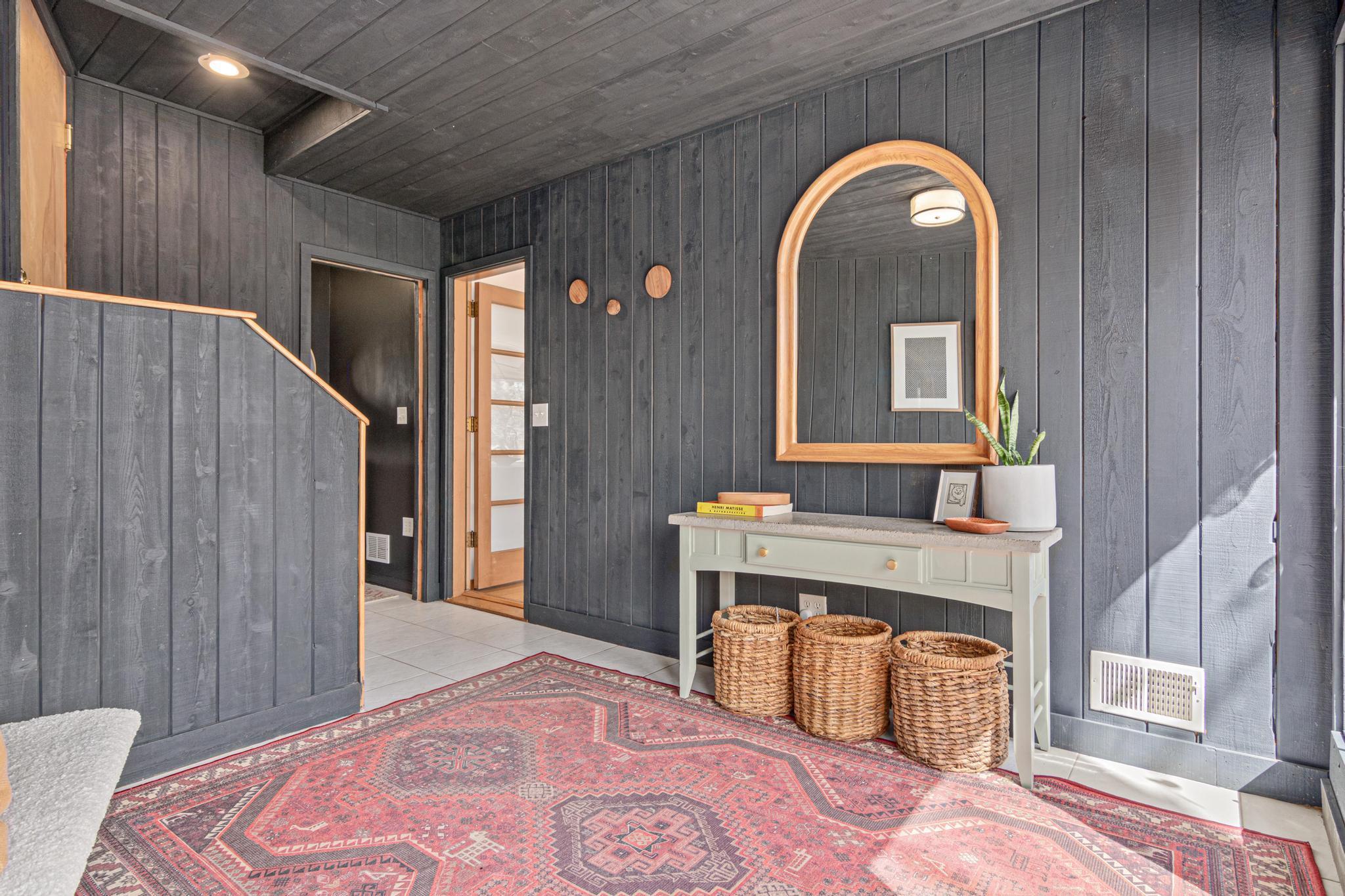 First impressions matter and this one delivers. The dramatic charcoal wood paneling, and warm wood accents give this entryway a personality that sets the tone for everything that follows.