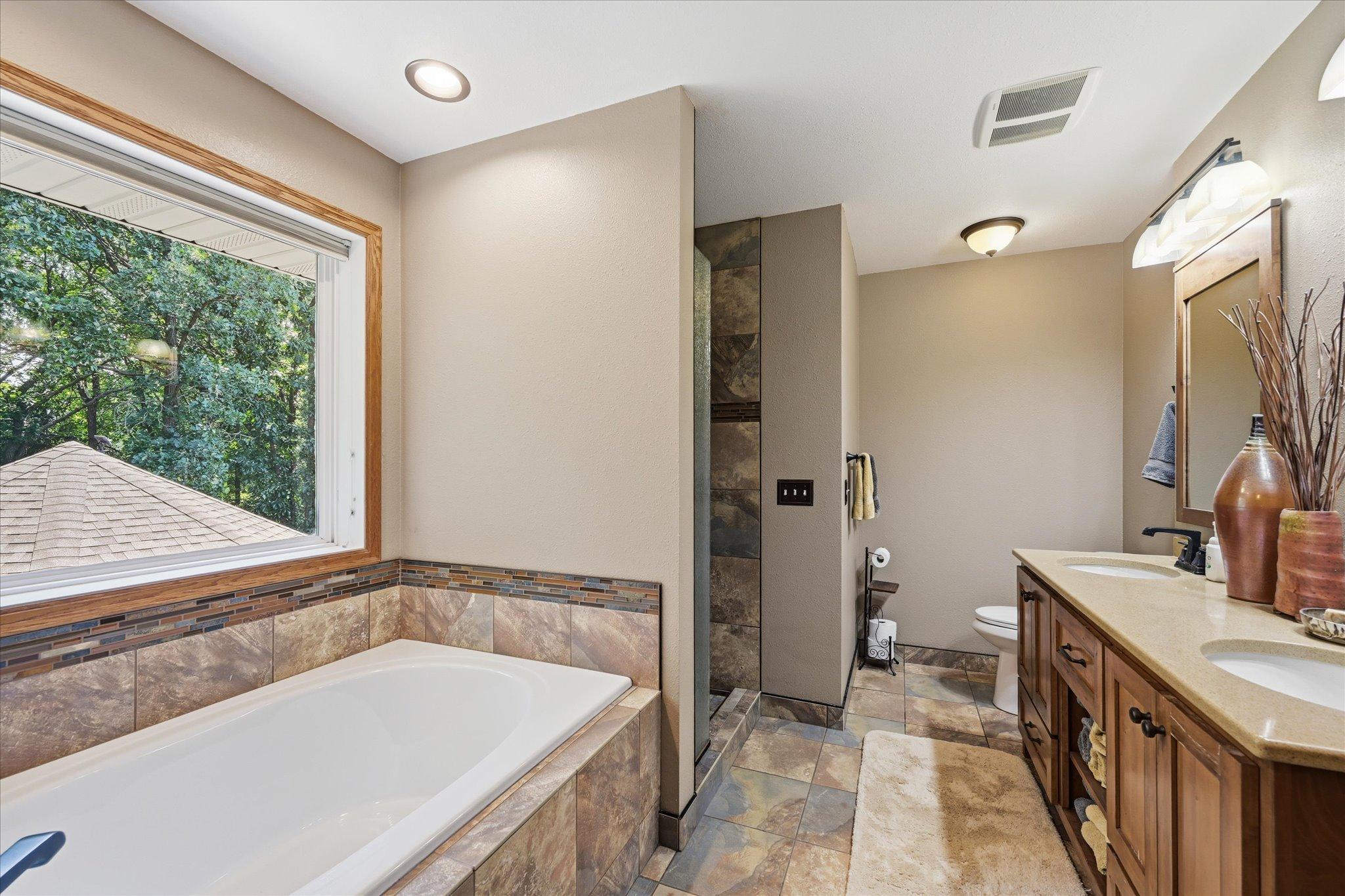 Private ensuite featuring a soaking tub, separate shower, and walk-in closet