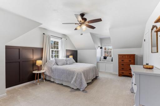 Primary bedroom featuring a striking custom board-and-batten accent wall, architectural sloped ceilings, and a built-in benchâcombining style and cozy functionality.