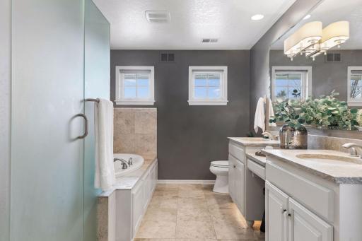The primary bath features a stone floor, double vanity, soaking tub and walk in shower with plenty of storage.
