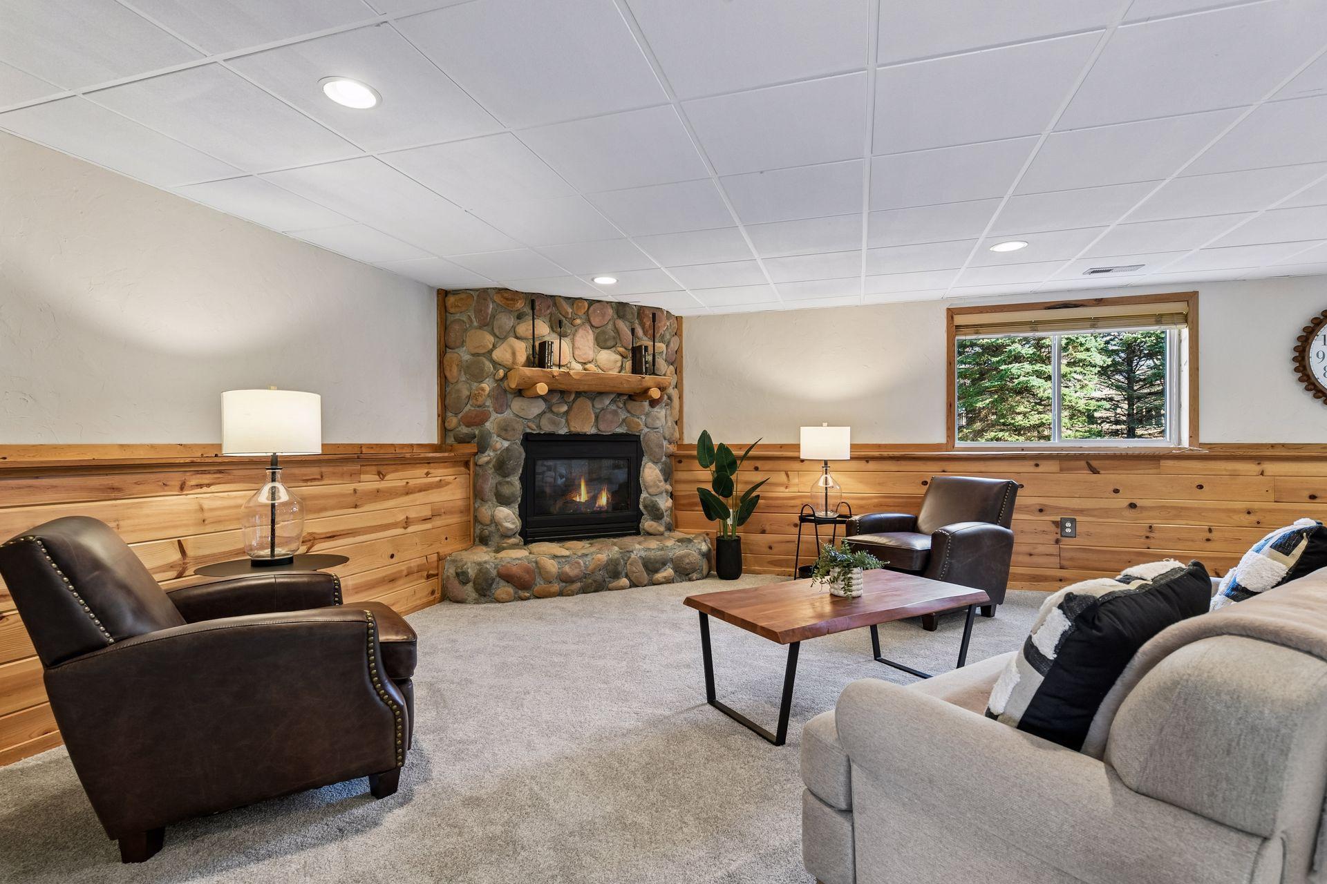 Many spots to entertain year-round in your new lower-level space. Stonefield fireplace with log mantle.
