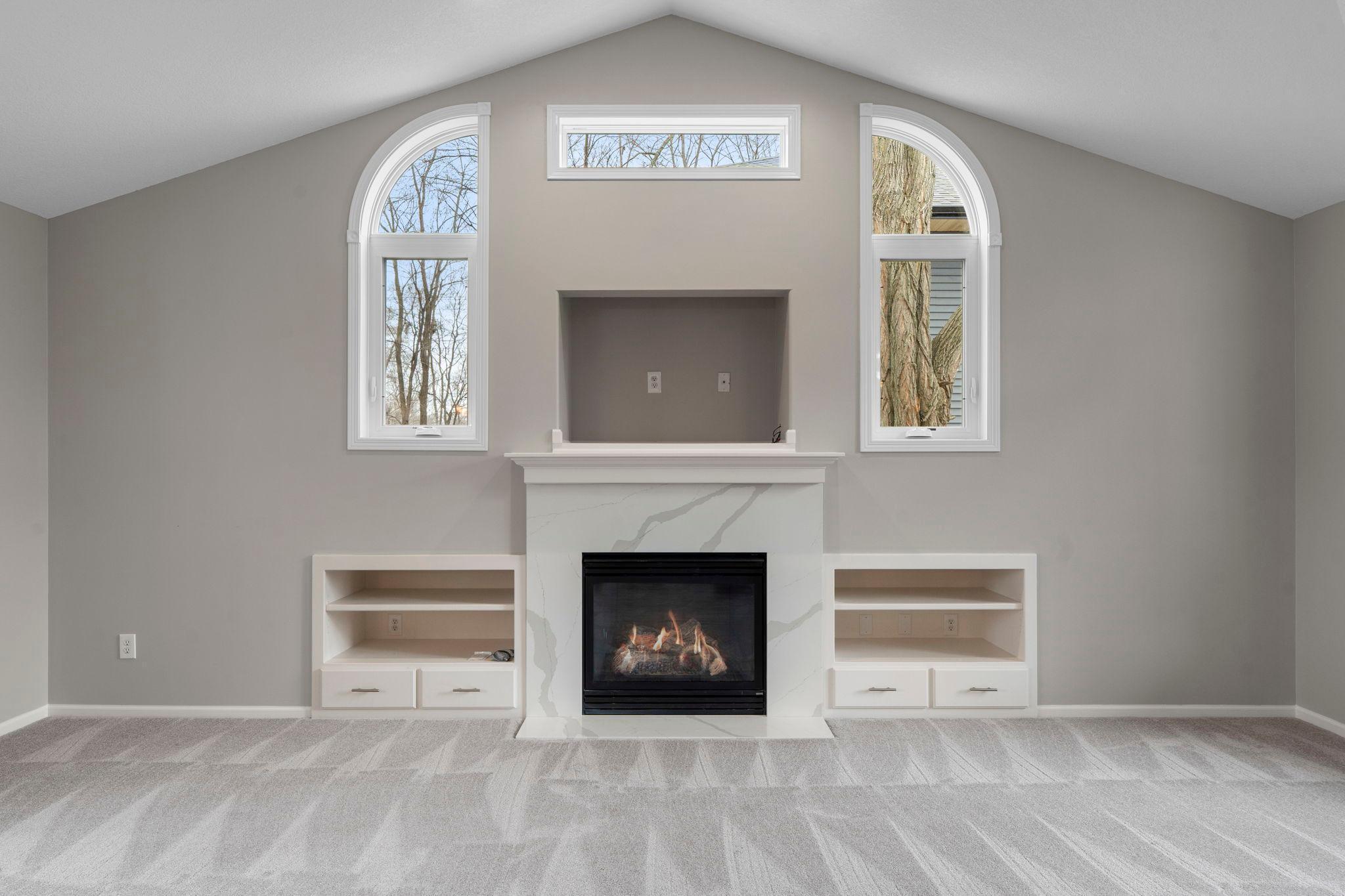 Gorgeous fireplace backdrop with quartz front, accented by unique curved windows!