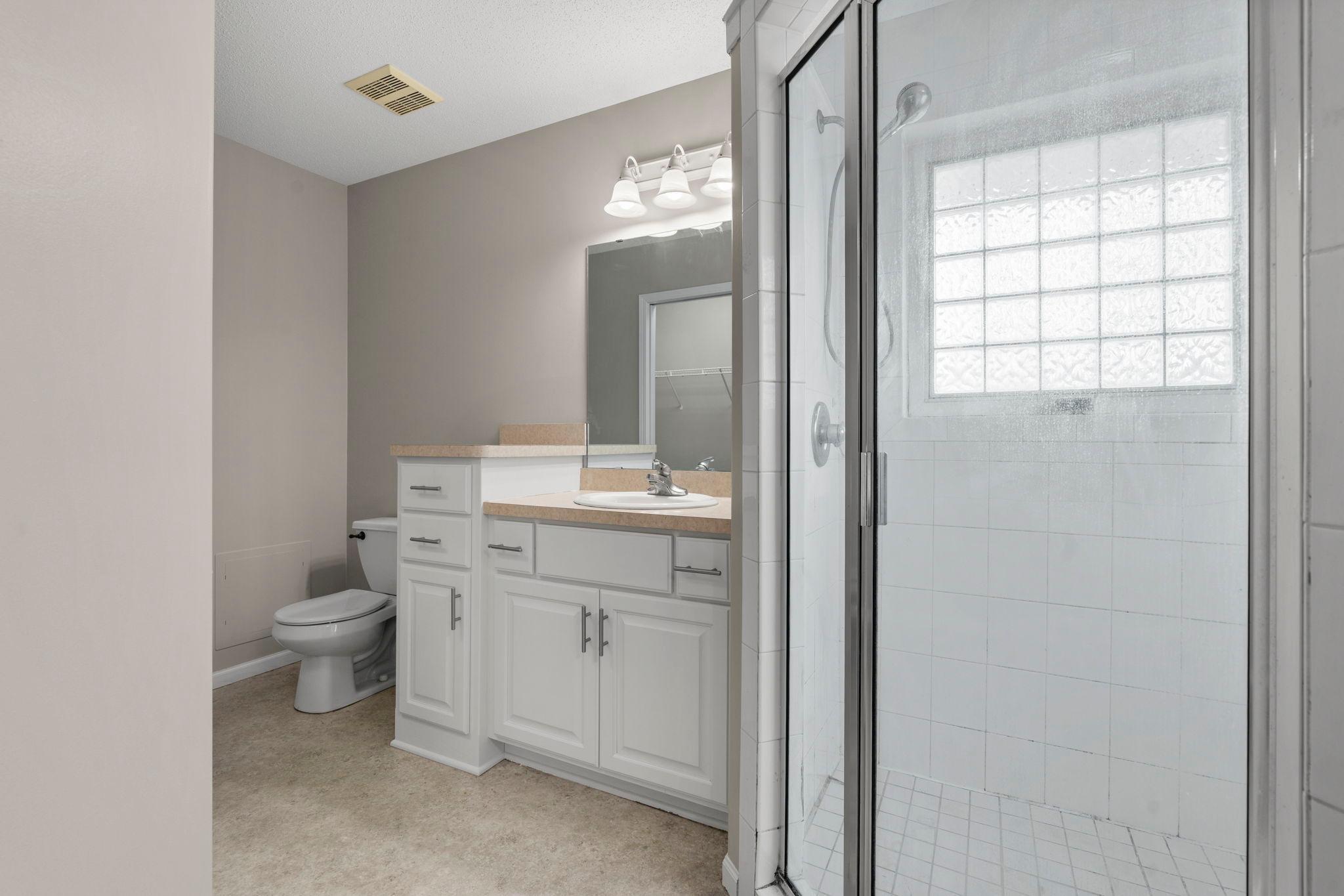 Primary bathroom with large tiled shower and seperate sinks and vanities. Abundance of storage drawers.
