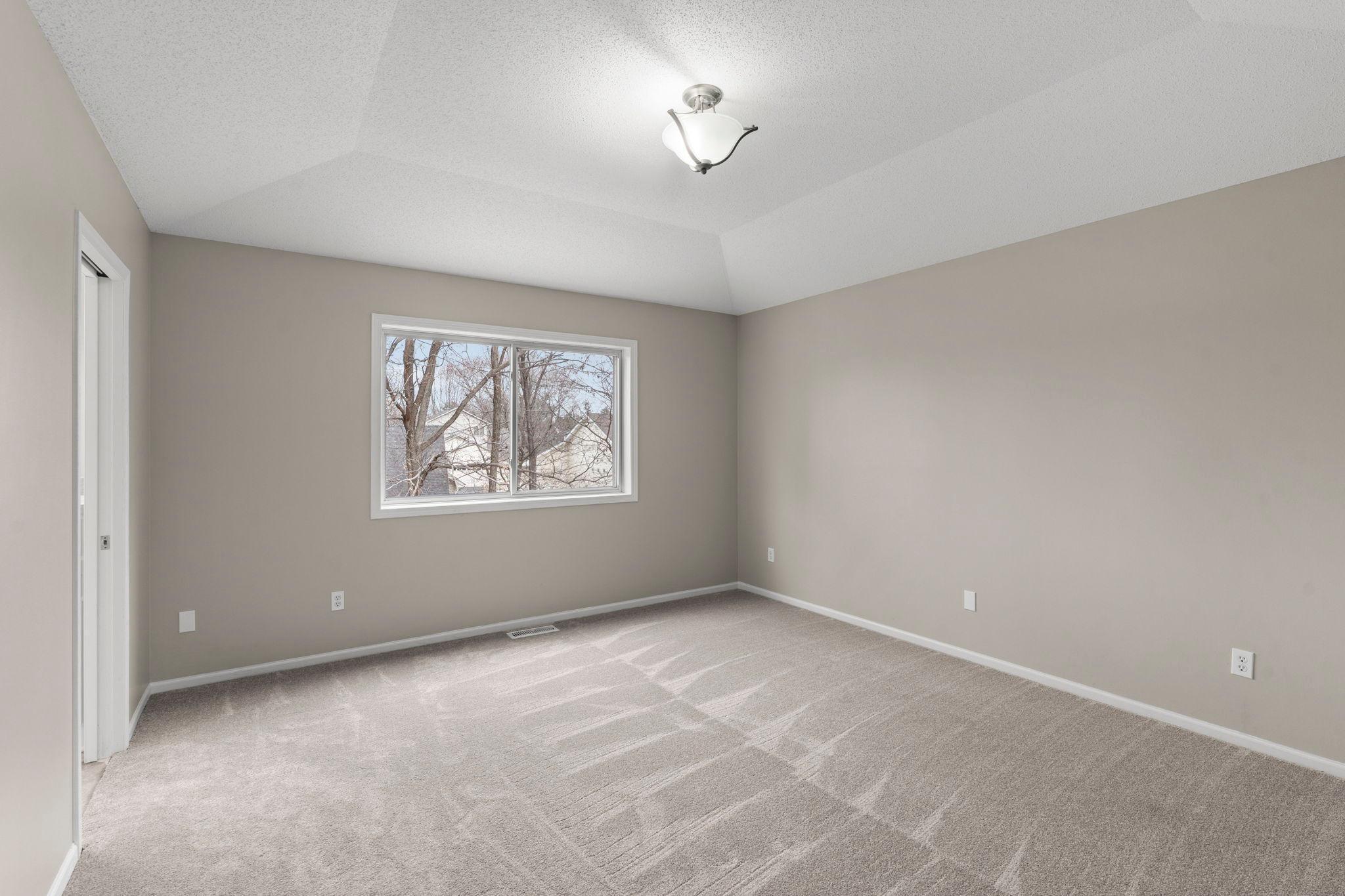 Primary suite features tray ceiling and large window.