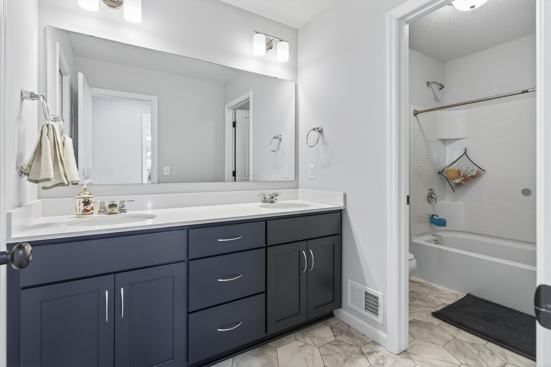 Full bath with dual sinks shared by bedrooms 2 and 3