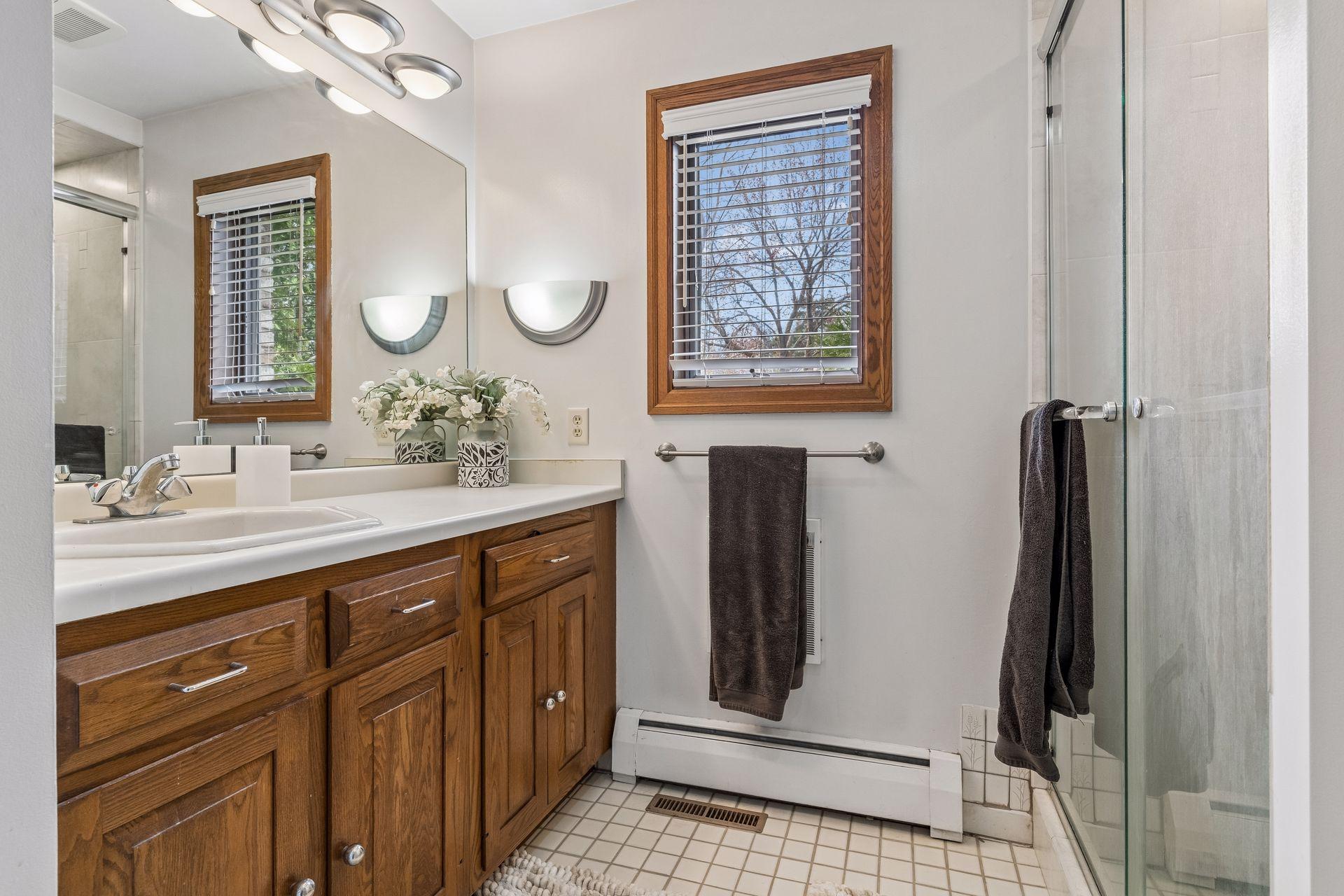 The separate side offers an updated tiled shower, second vanity, and toilet—ideal for busy mornings.