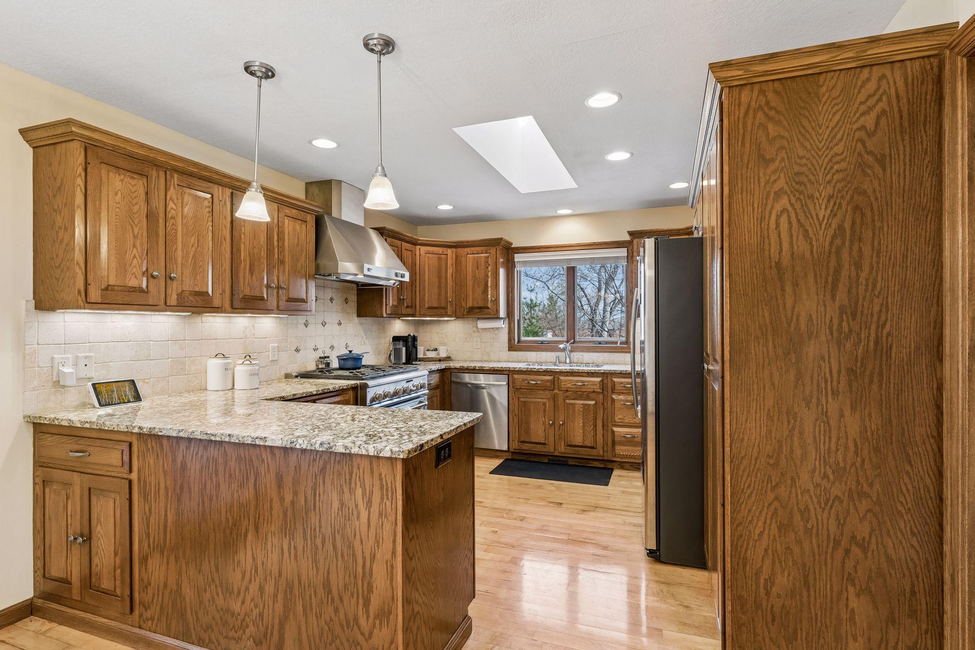 Spacious Kitchen has Granite countertops, tile backsplash and maple wood floors.