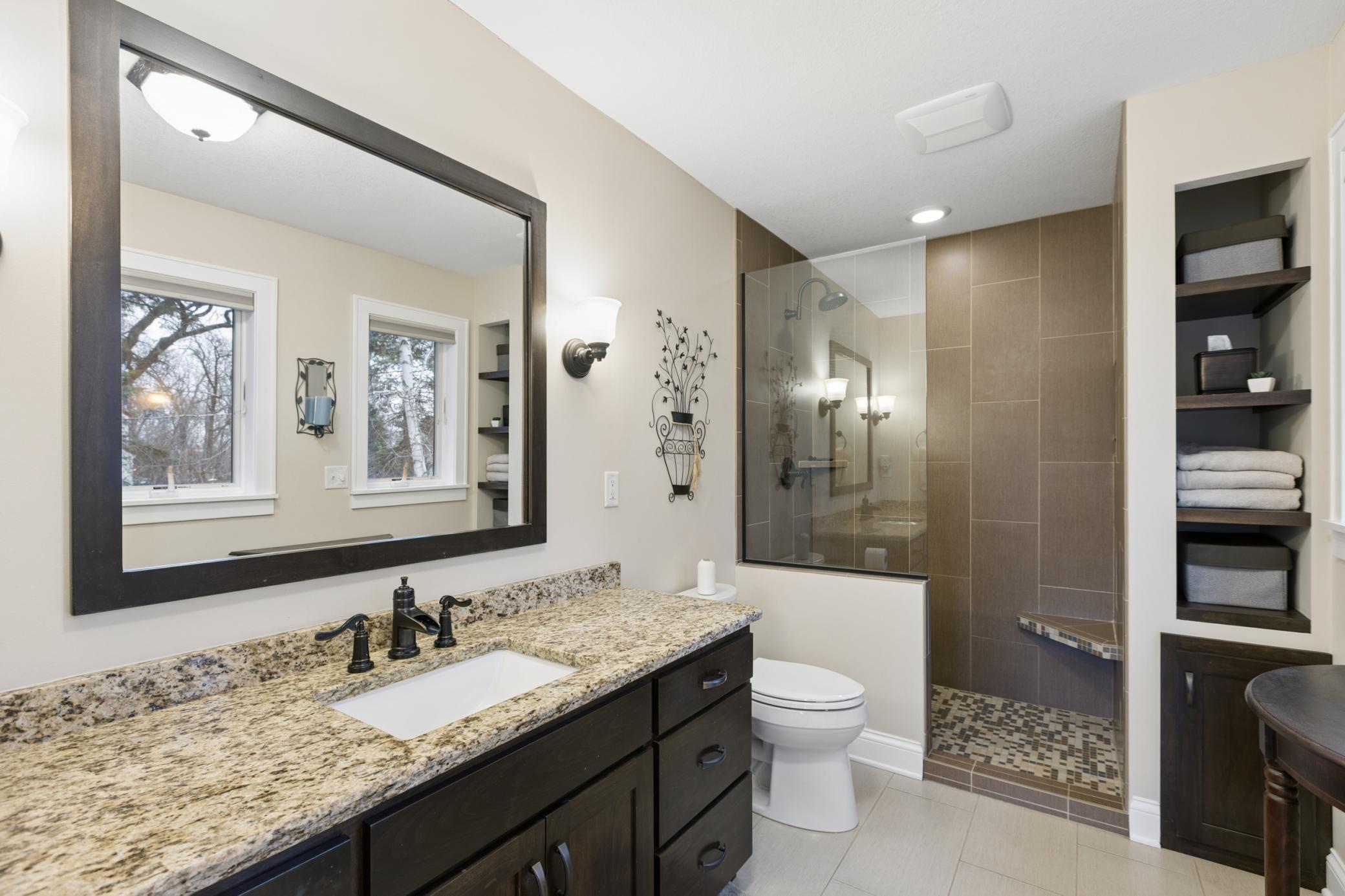 View of the ensuite bathroom with tile floors and a tile walk-in shower with bench.