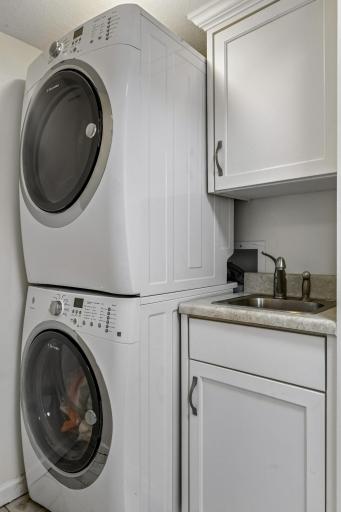 The laundry room with utility sink and stacked washer & dryer is set off the mud room.