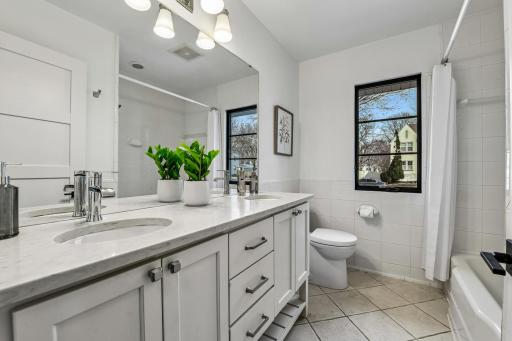 The primary full bath is well-appointed with tile finishes and a dual vanity with quartz counter.
