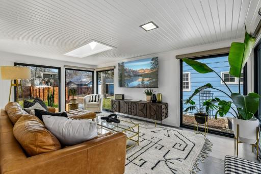 Inviting sun room is wrapped in windows and features cork flooring, tongue-n-groove ceiling, skylight and opening to the kitchen.
