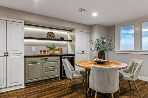 A dry bar with tons of storage, a beverage fridge and open shelving with accent lighting offer functionality to this great rec area.