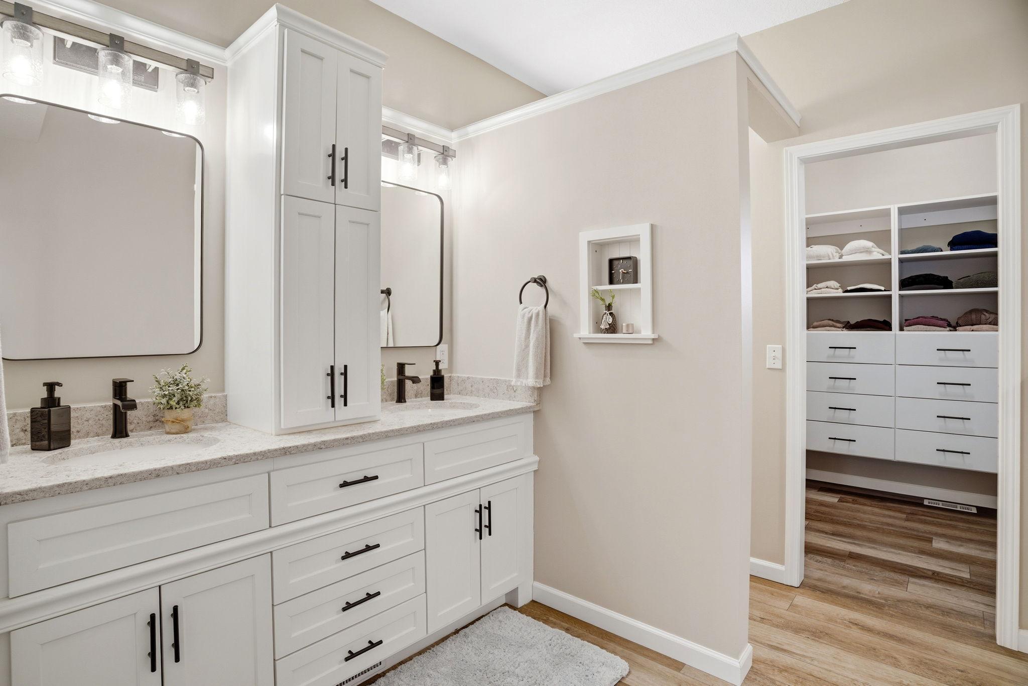 Beautifully updated main-level primary bath featuring a new layout, dual sinks, soaking tub, walk-in shower, and a spacious closet with custom cabinetry.