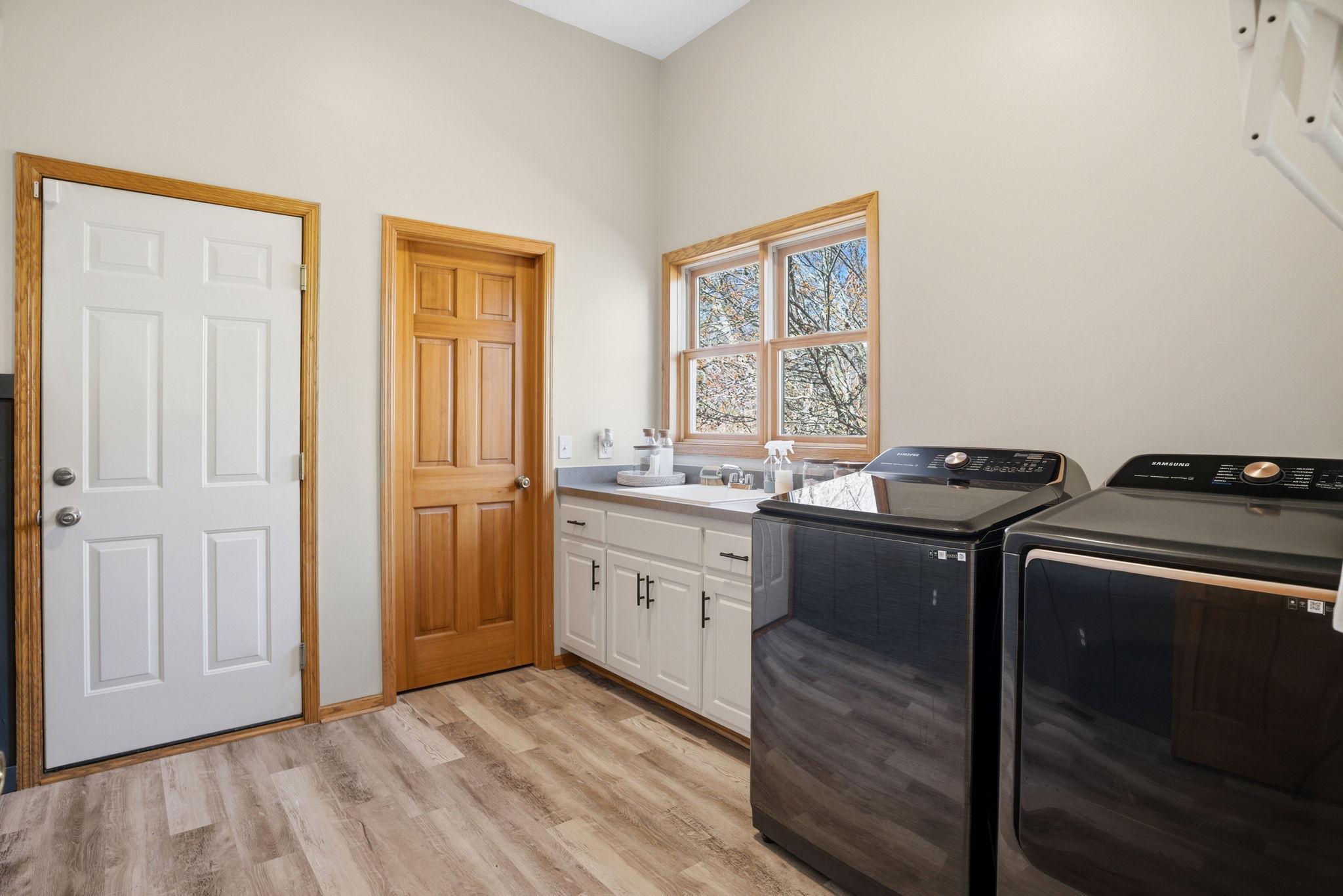 Just off the half bath, the large mudroom features a washer, dryer, utility sink, spacious walk-in closet for coats and shoes, ample storage, and access to the three-stall garage. Updated Flooring!