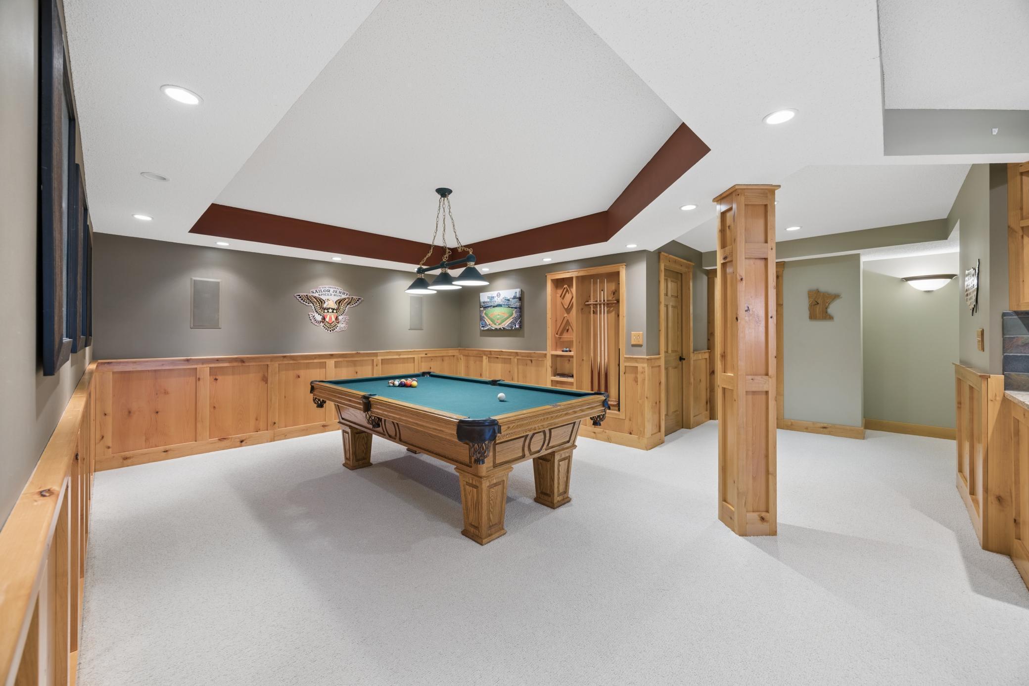 The lower level truly stands out & is ideal for entertaining all ages w/ 9-ft ceilings, warm wood wainscoting, and a pool room