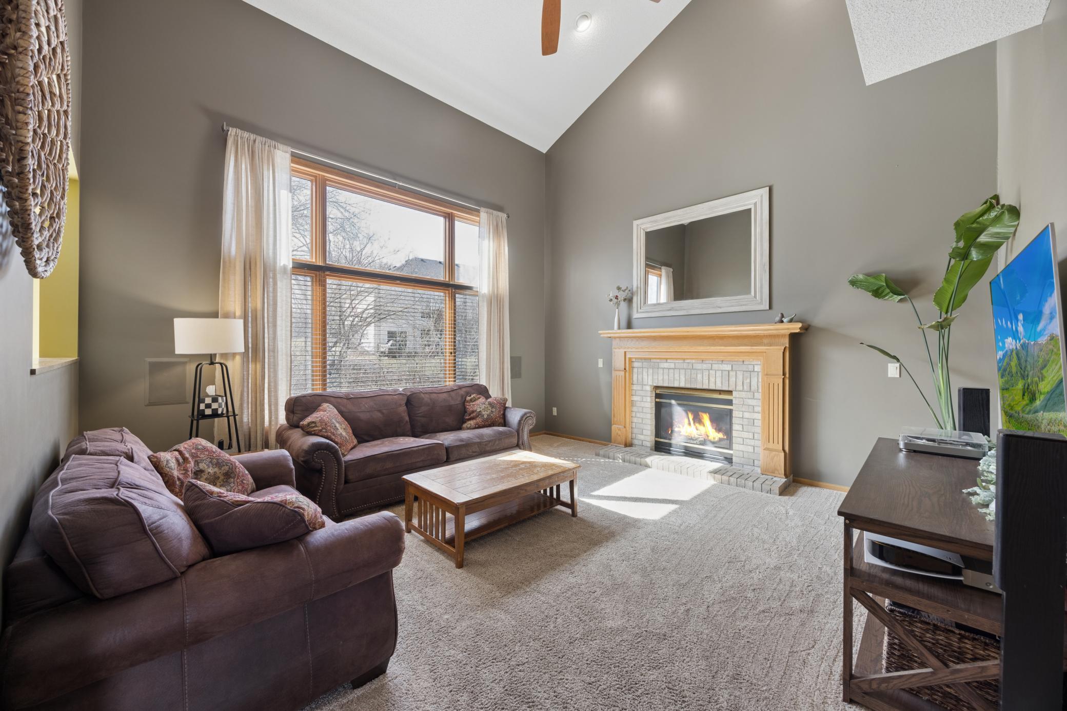 Two Story living room with sun filled windows and gas fireplace