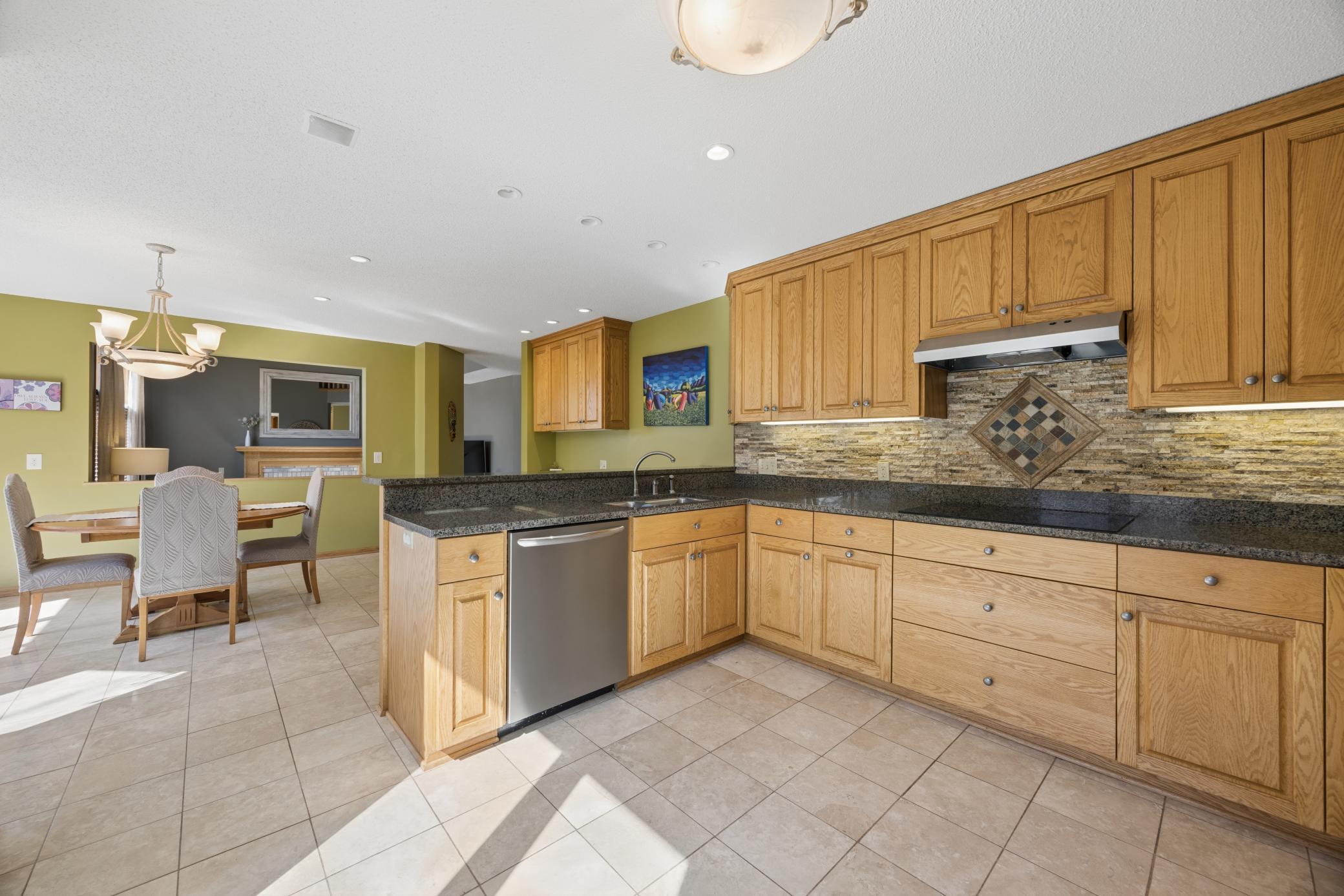 Kitchen area offers desirable features like granite countertops w/ breakfast bar, tile floor, stone backsplash, stainless steel appliances, and a built-in desk