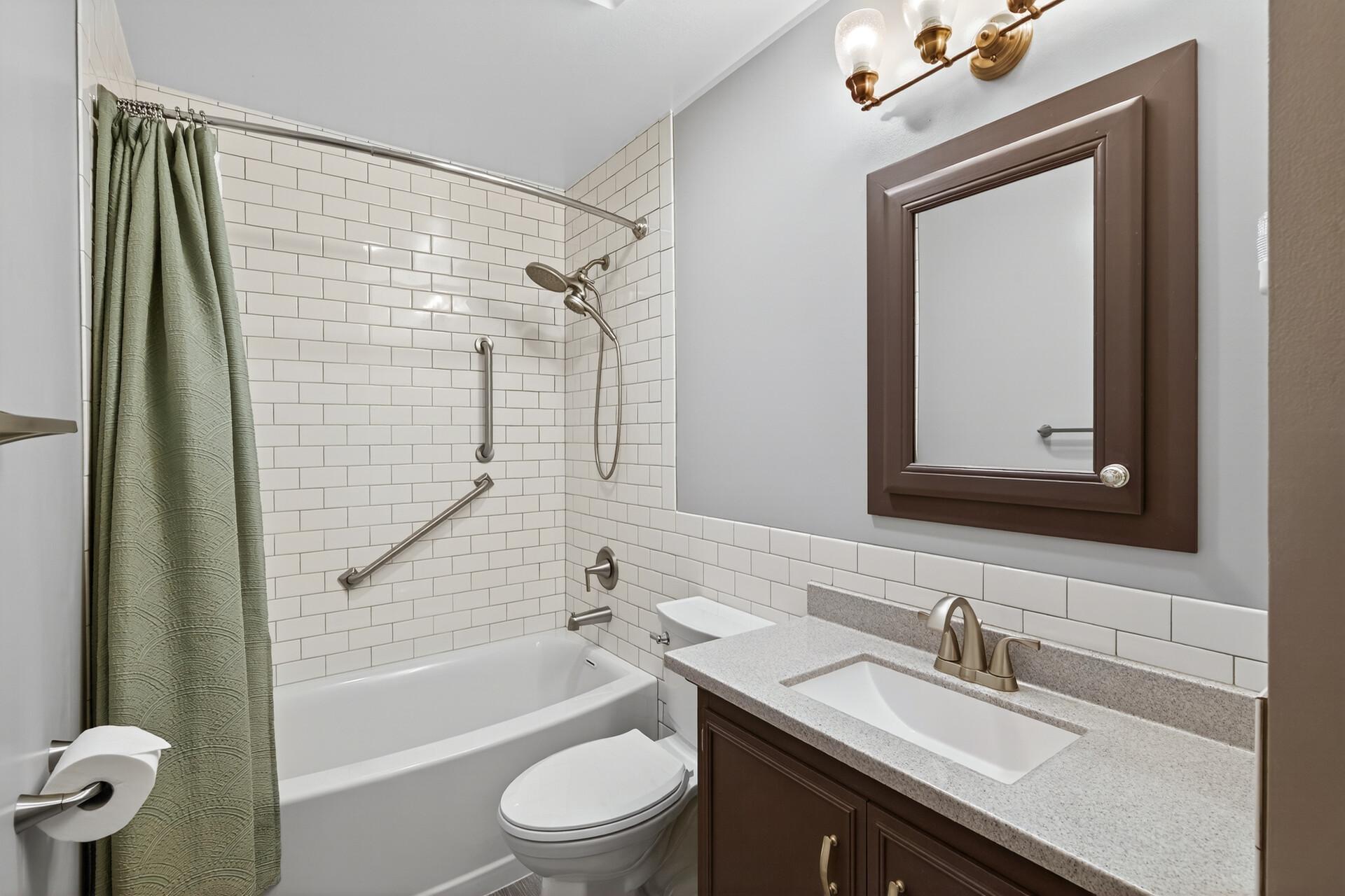 Recently updated bathroom featuring a new vanity and a subway tile tub and shower surround.
