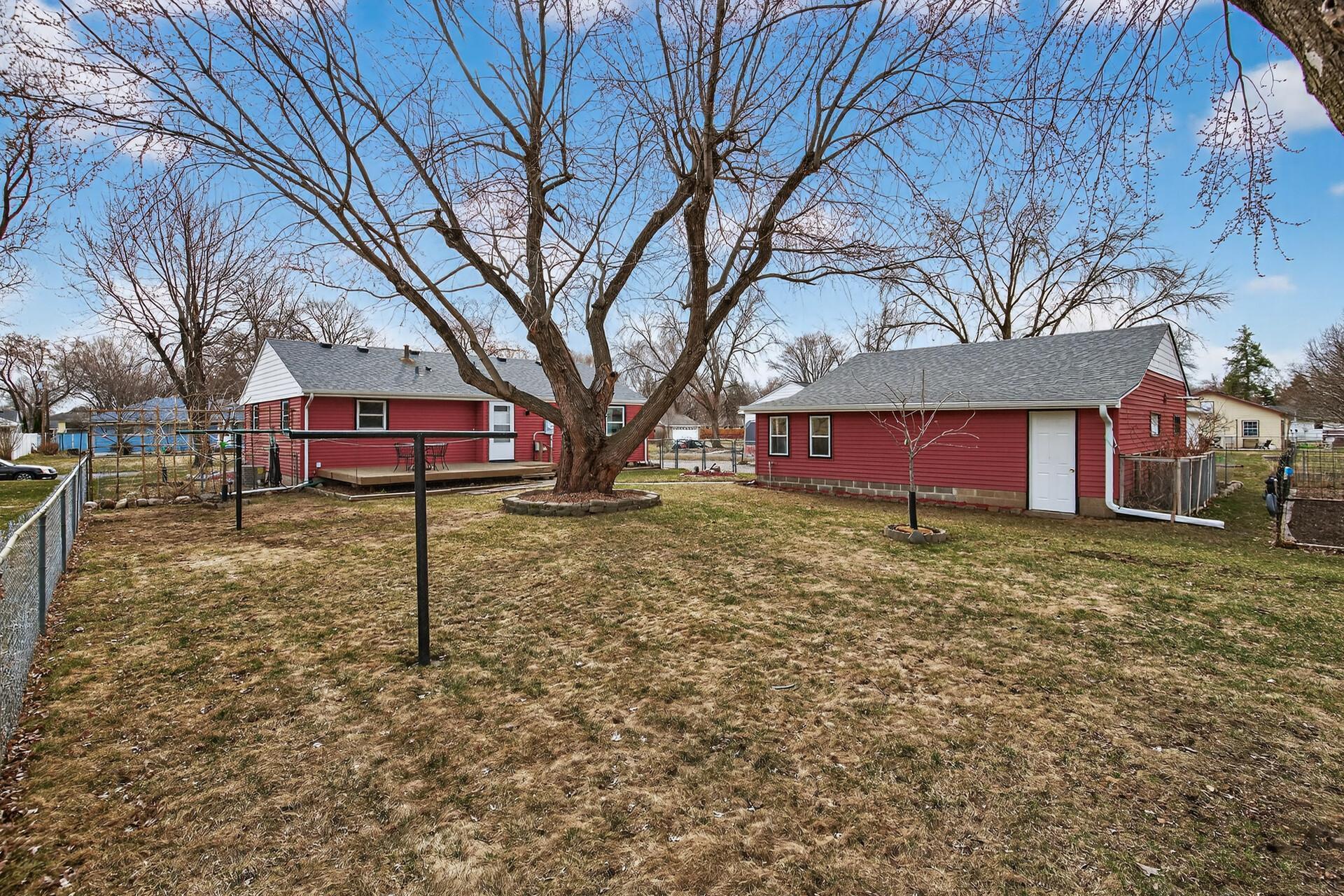 Large, fully fenced backyard lined with mature oak trees.
