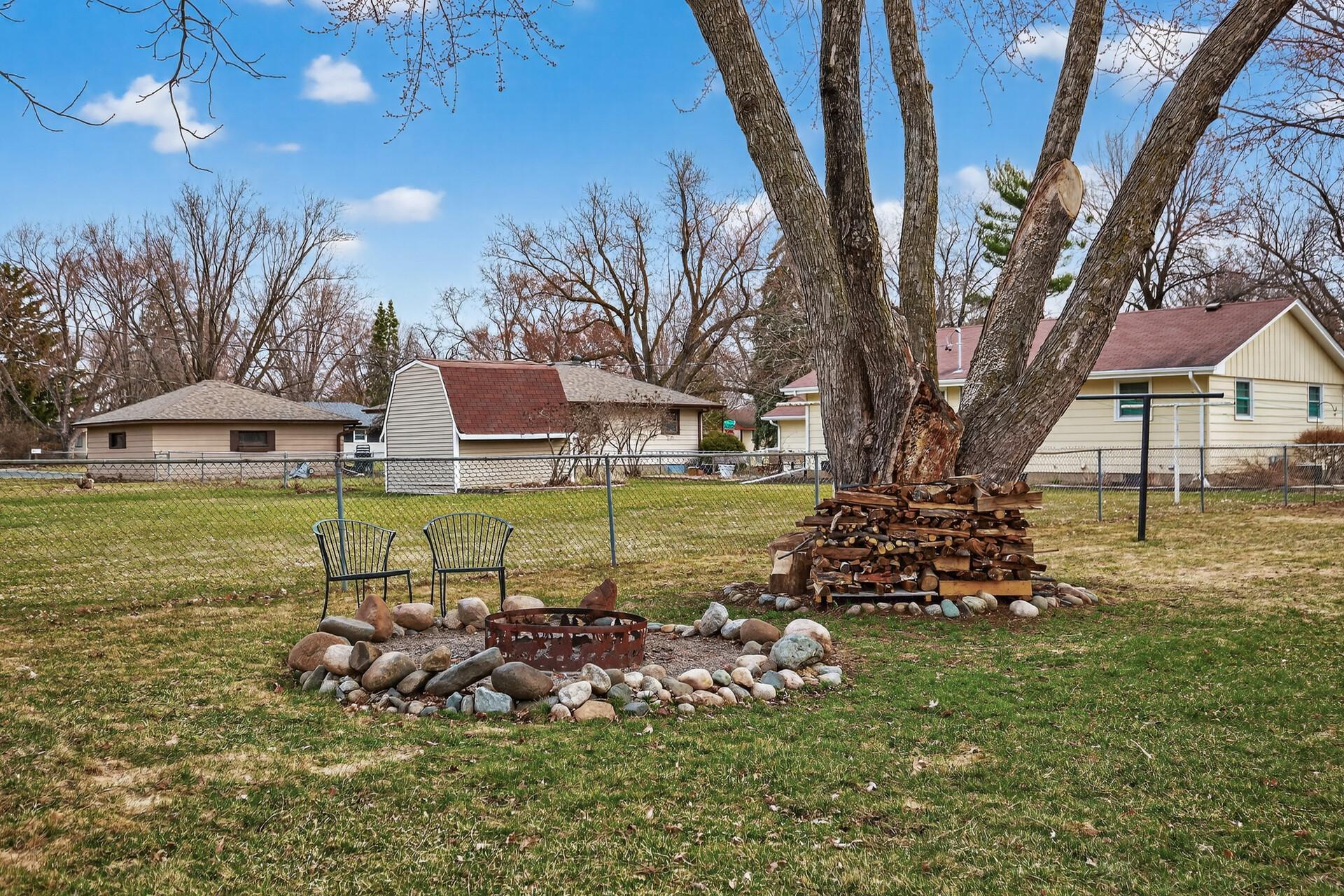 Spacious fenced yard featuring established oak trees and a firepit.
