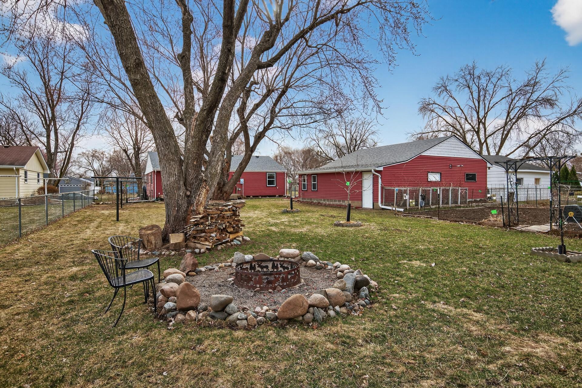 Large, fully fenced backyard with mature oak trees and a built-in firepit.