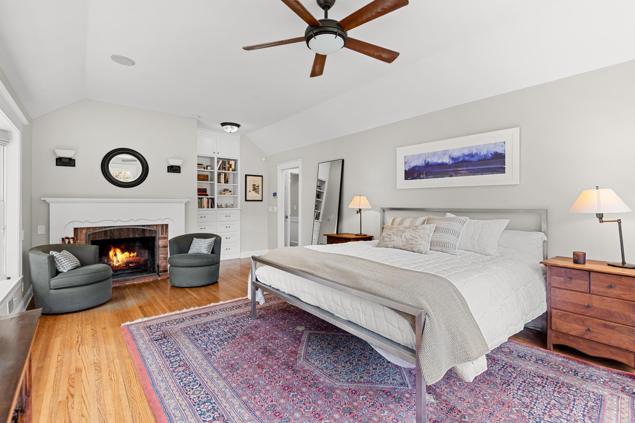Primary suite warm with fireplace and enriched by floors and built-ins