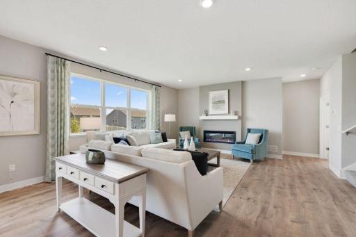 Main floor family room with large windows and cozy electric fireplace. Photos of model, options may vary.