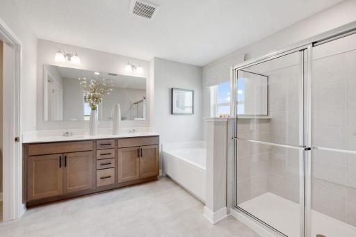 The primary bath is a perfect oasis to escape to. Featuring dual vanity, quartz countertops, walk in shower, and soaking tub. Photos of model, options may vary.