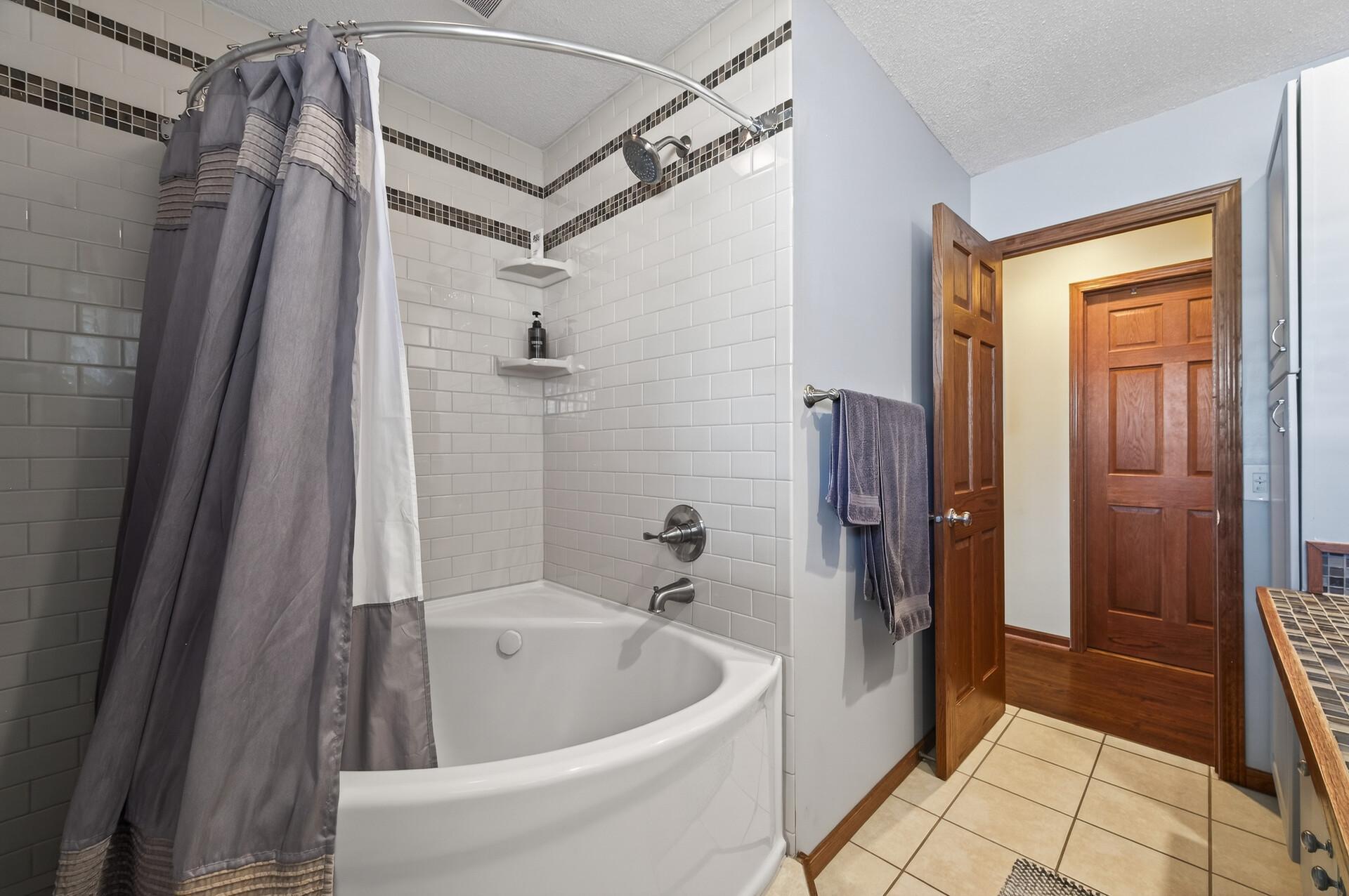 Soaking tub/shower with tile surround.