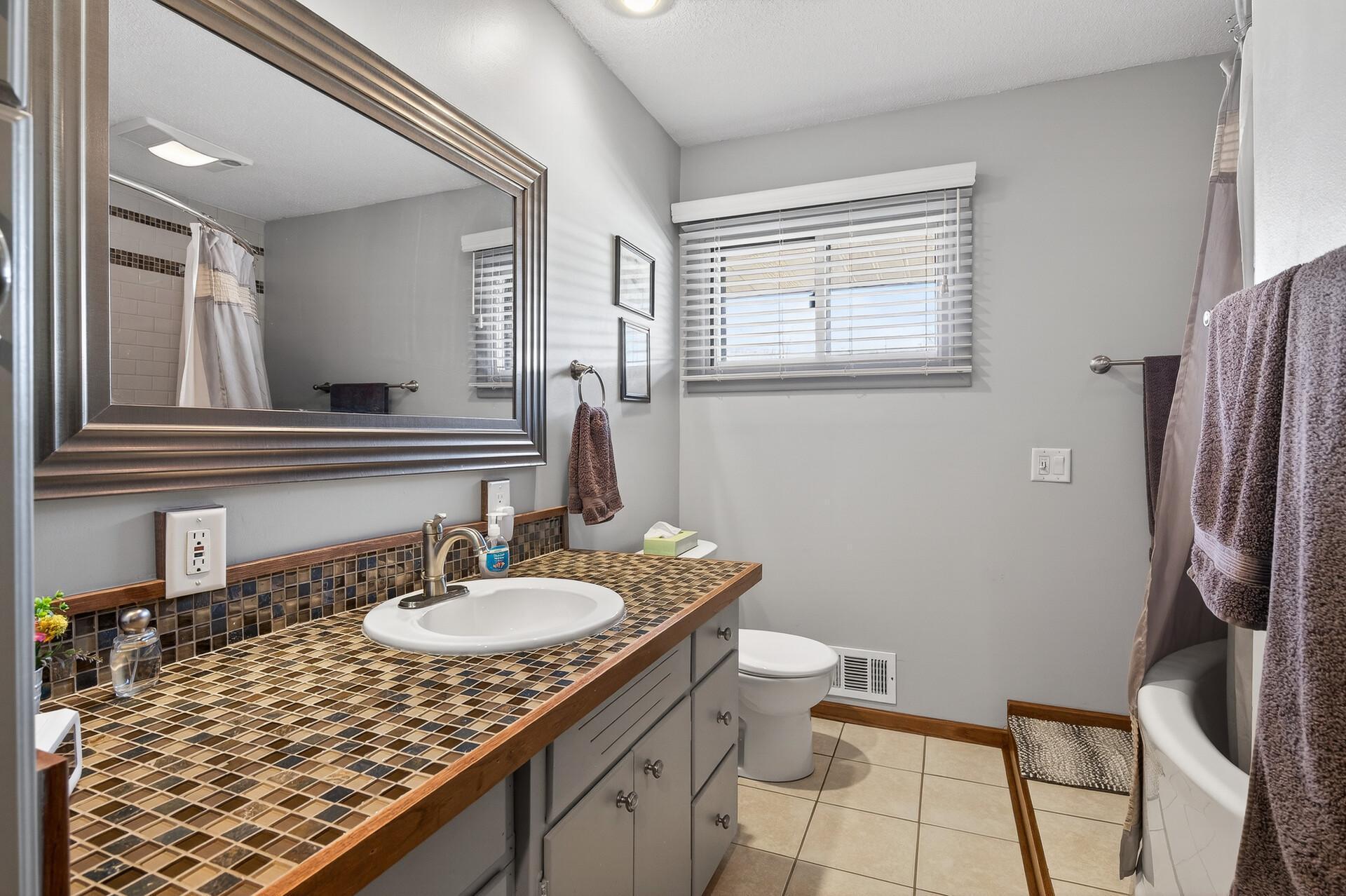 Main level full bathroom with tile top vanity.