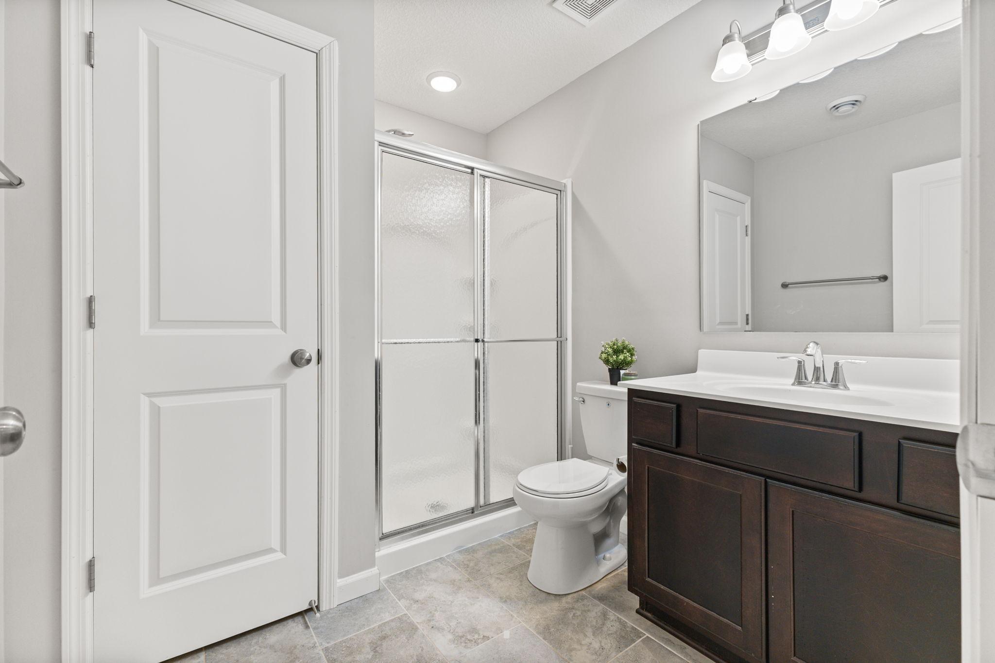 Lower-level 3/4 bath with a spacious vanity and generous storage, featuring a clean layout and walk-in shower.