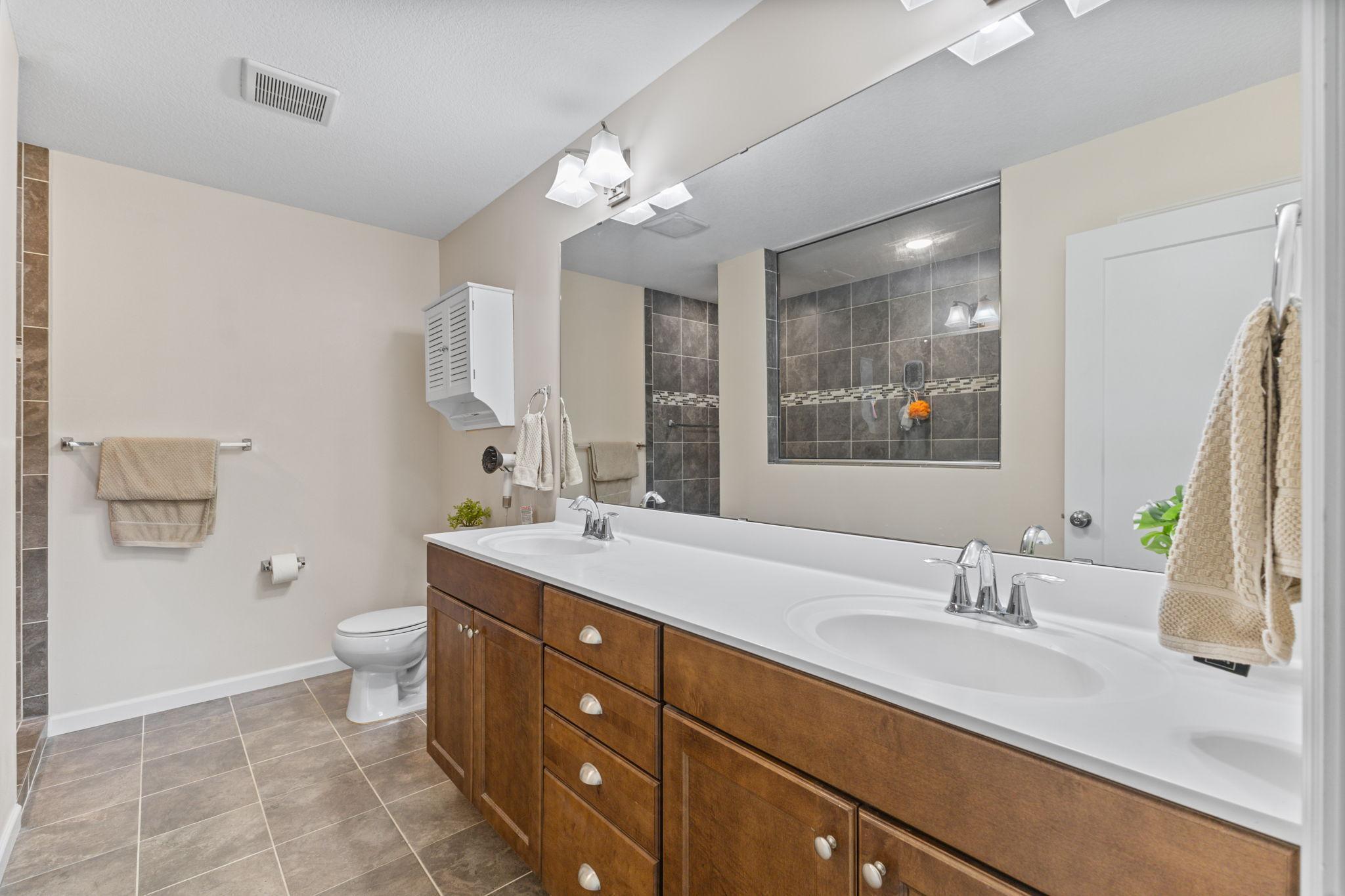 Spacious primary ensuite featuring a double vanity with ample storage and a large mirror. Includes a tiled walk-in shower and a functional layout designed for everyday comfort and convenience.