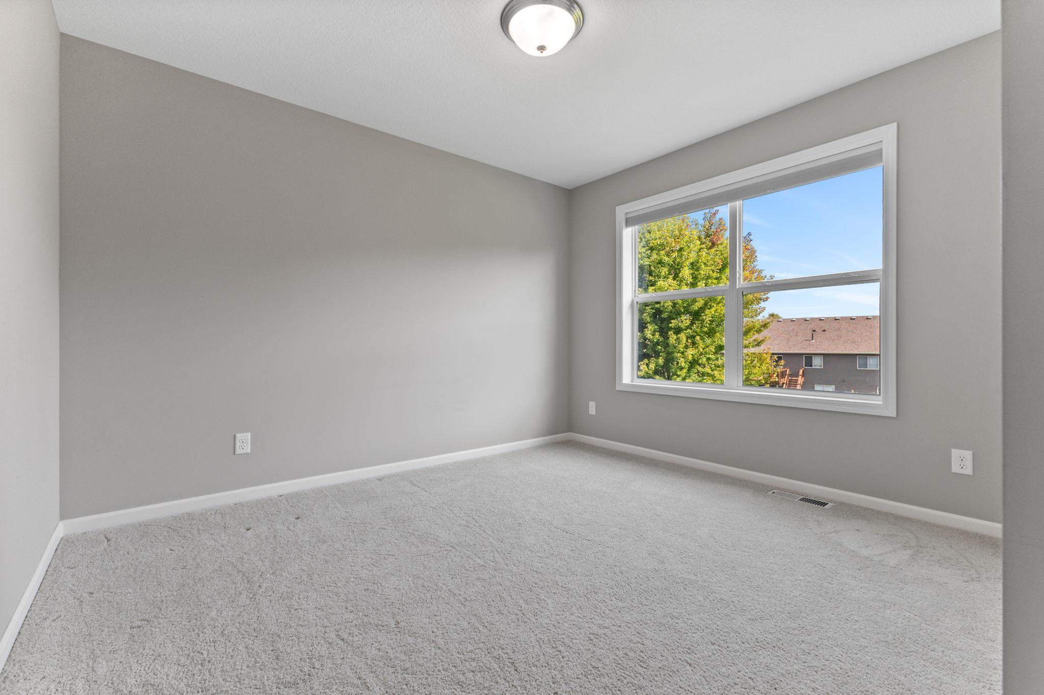 Upstairs bedroom with east-facing window overlooking the backyard, bringing in natural morning light. Clean, neutral space with plenty of room for a full bedroom setup.