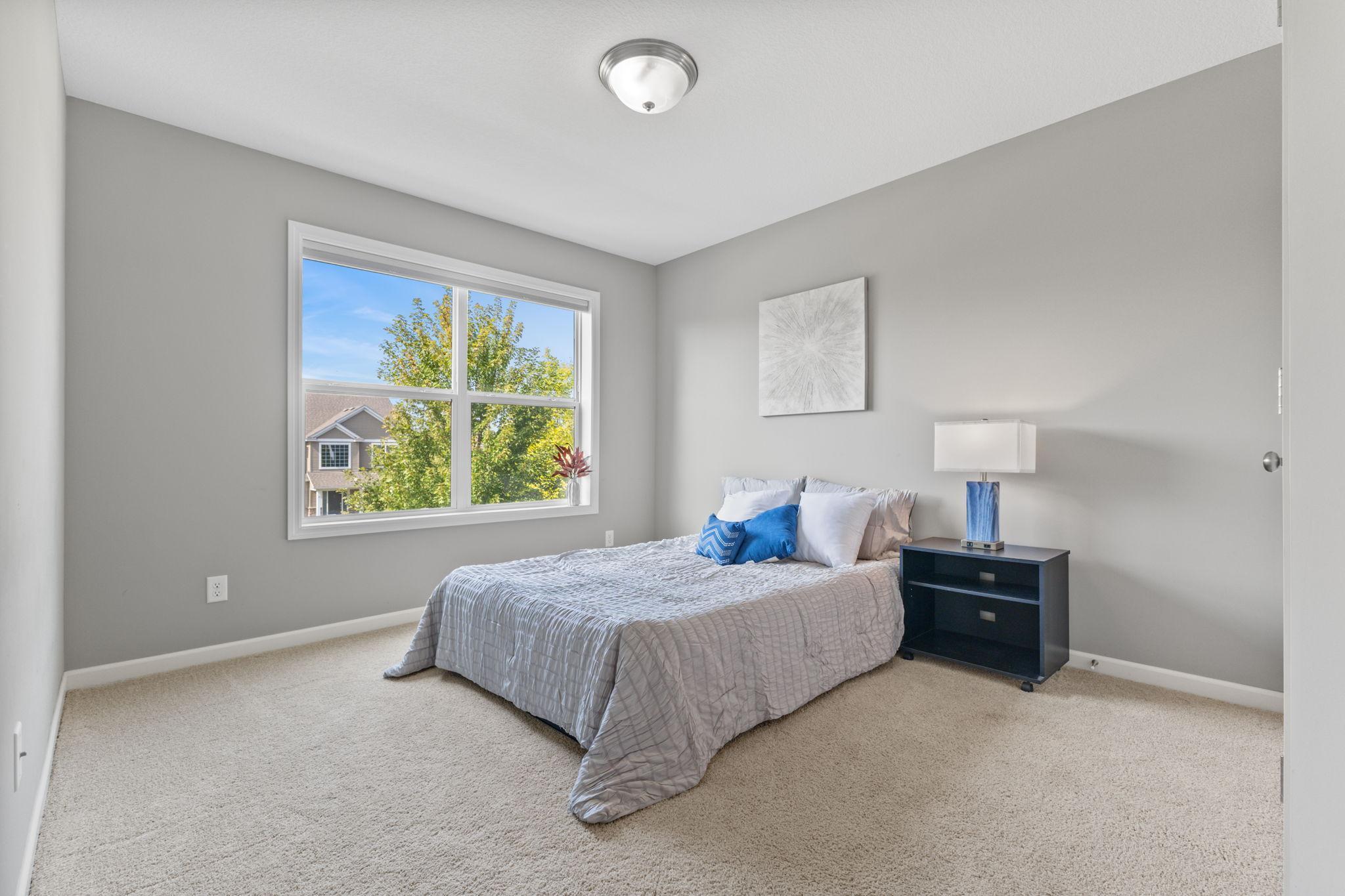 West-facing bedroom filled with afternoon light, featuring a clean, neutral layout and ample space for a full bedroom setup.