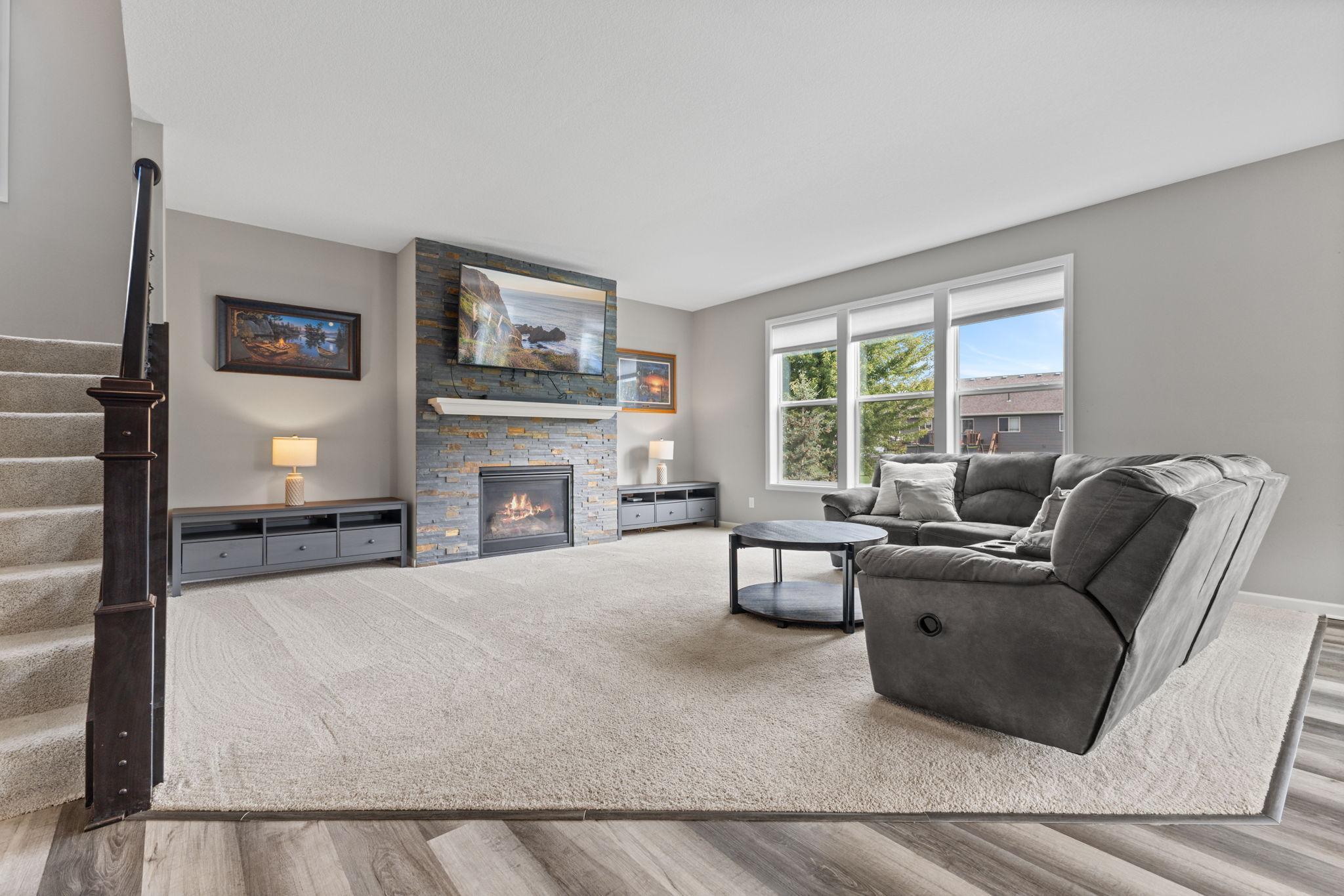 A floor-to-ceiling stone gas fireplace serves as a stunning focal point, complemented by custom blinds throughout the home.