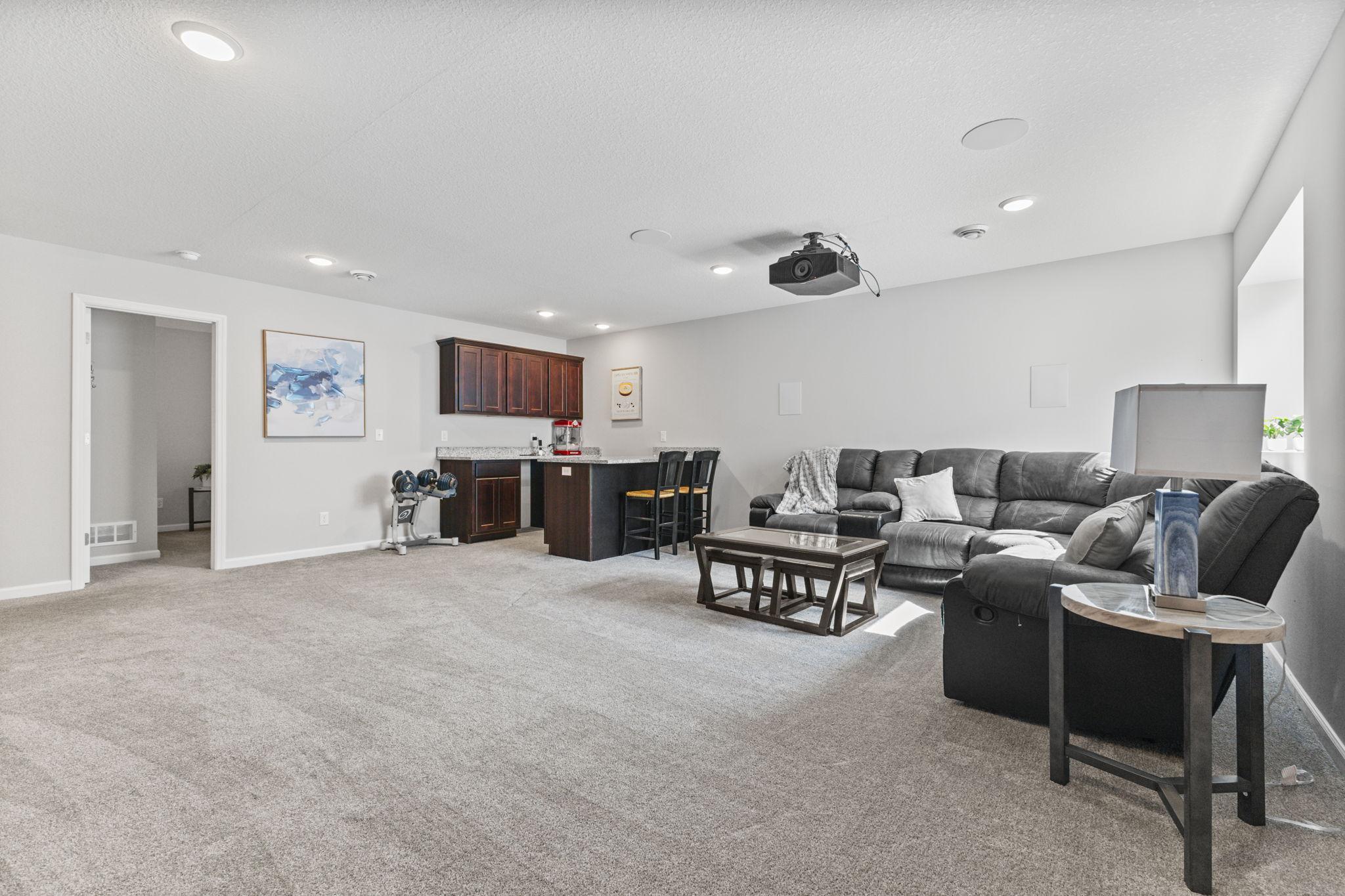 Expansive lookout lower-level family room with plenty of space for lounging and entertaining, featuring a built-in bar area and an open layout that easily accommodates multiple uses.