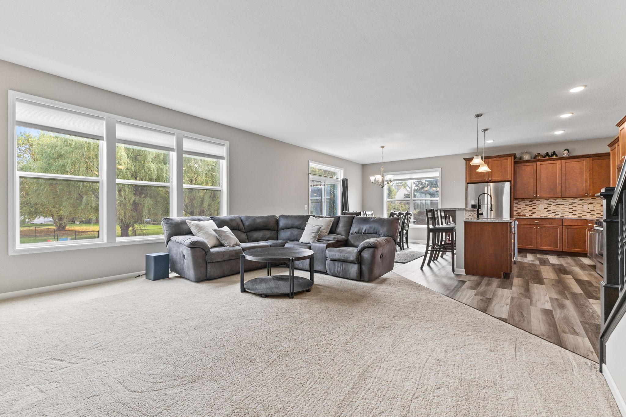 Open main living area with expansive windows bringing in natural light and backyard views. Seamless flow into the kitchen and dining space creates an ideal layout for everyday living and entertaining.