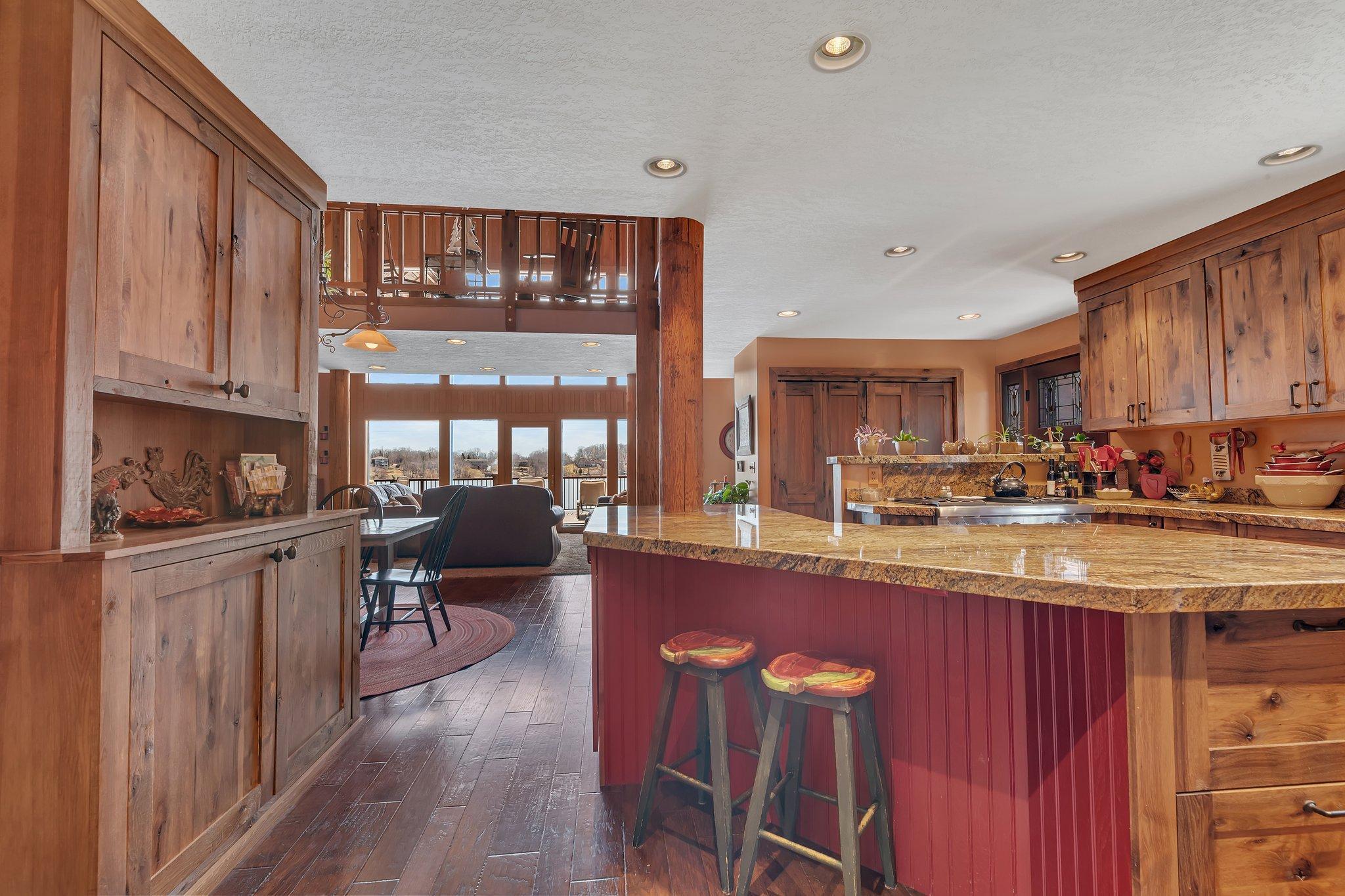 A warm, rustic kitchen opens to a stunning lake view, blending cozy cabin charm with inviting natural light.