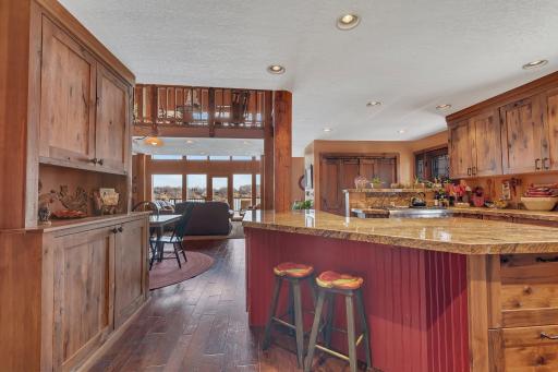 A warm, rustic kitchen opens to a stunning lake view, blending cozy cabin charm with inviting natural light.