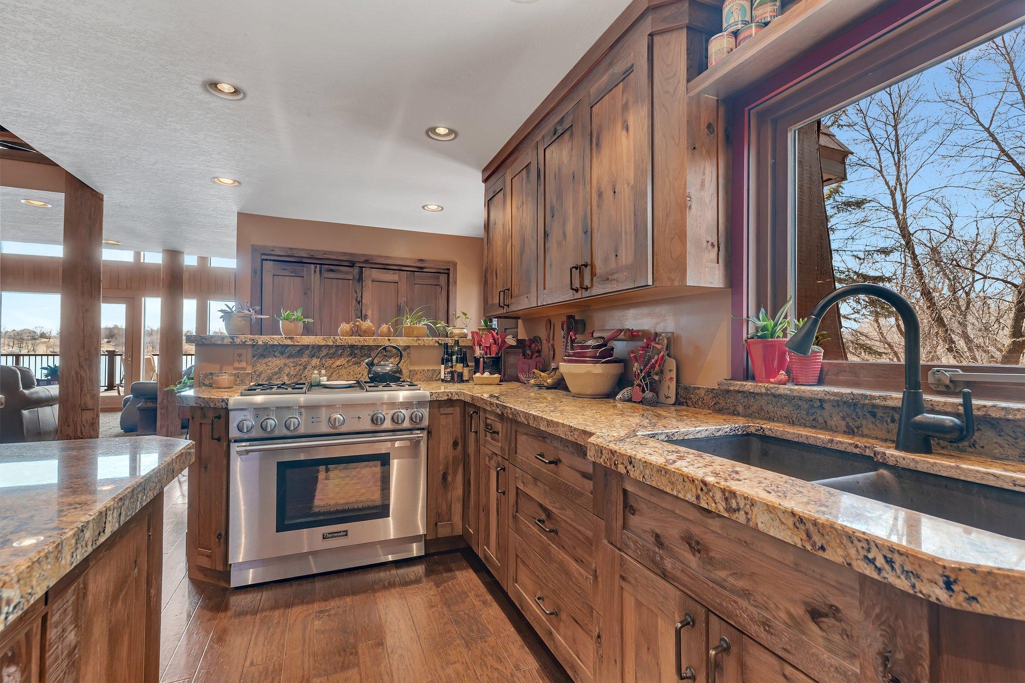 This inviting kitchen features rich wood cabinetry, granite countertops, and a large window that fills the space with natural light.