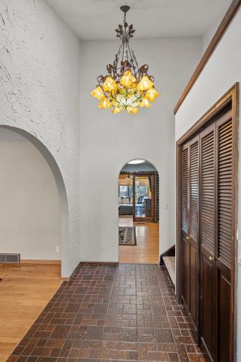 A dramatic front foyer with soaring ceilings, rich tile flooring, warm wood trim, generous closet space, and graceful arched openings that beautifully introduce the home’s Spanish-inspired character.