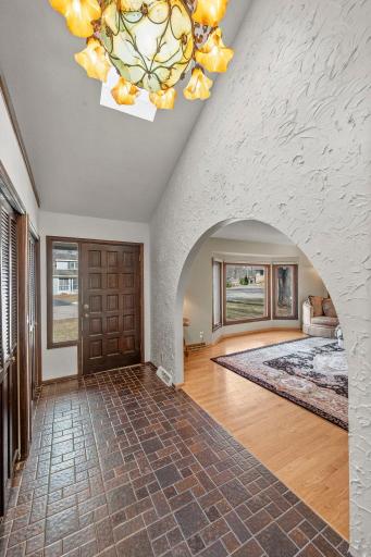 A dramatic front foyer with soaring ceilings, rich tile flooring, warm wood trim, generous closet space, and graceful arched openings that beautifully introduce the home’s Spanish-inspired character.